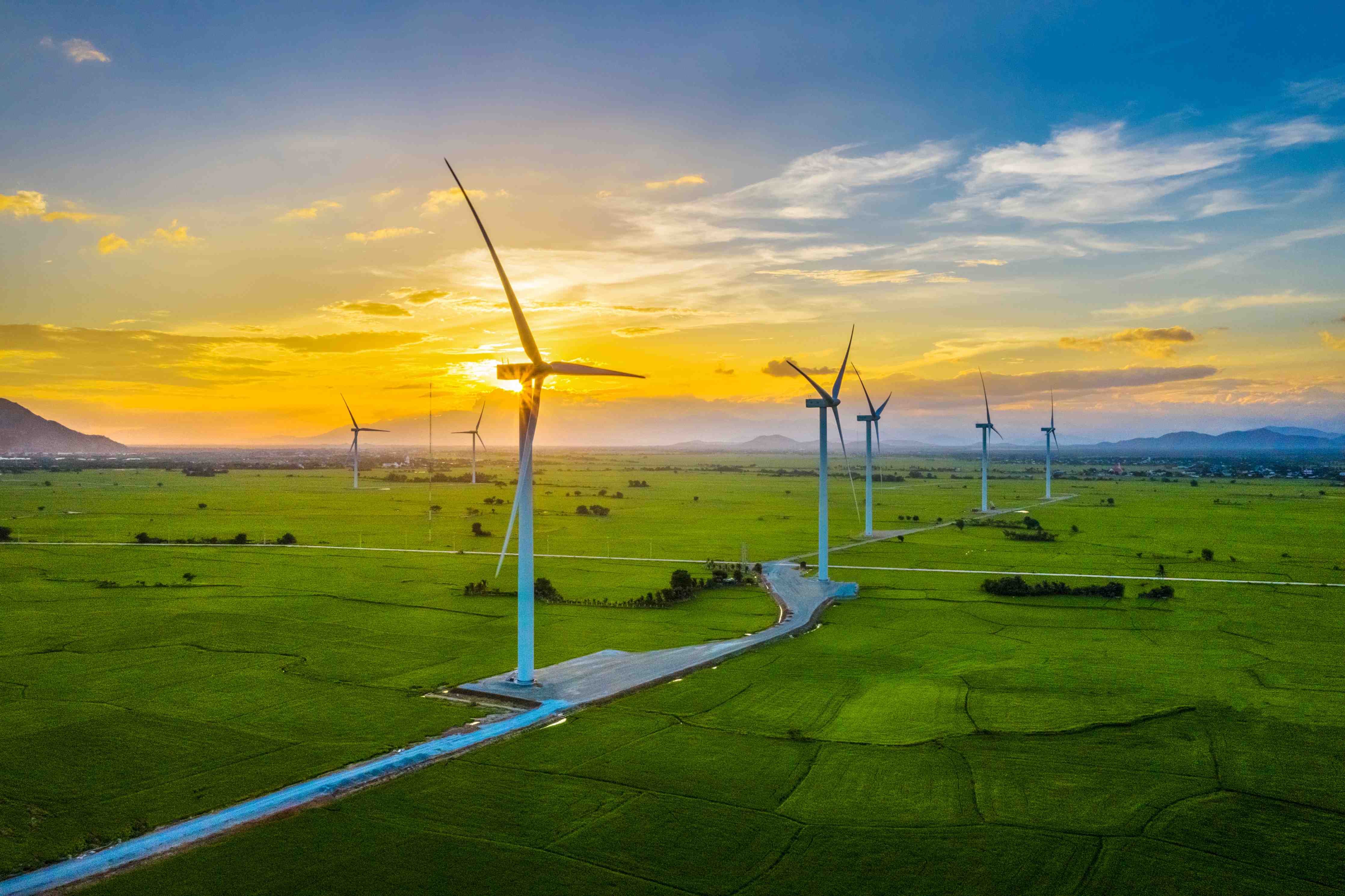 Große Wandbilder-Wind turbines bei Sonnenuntergang über grüner Landschaft