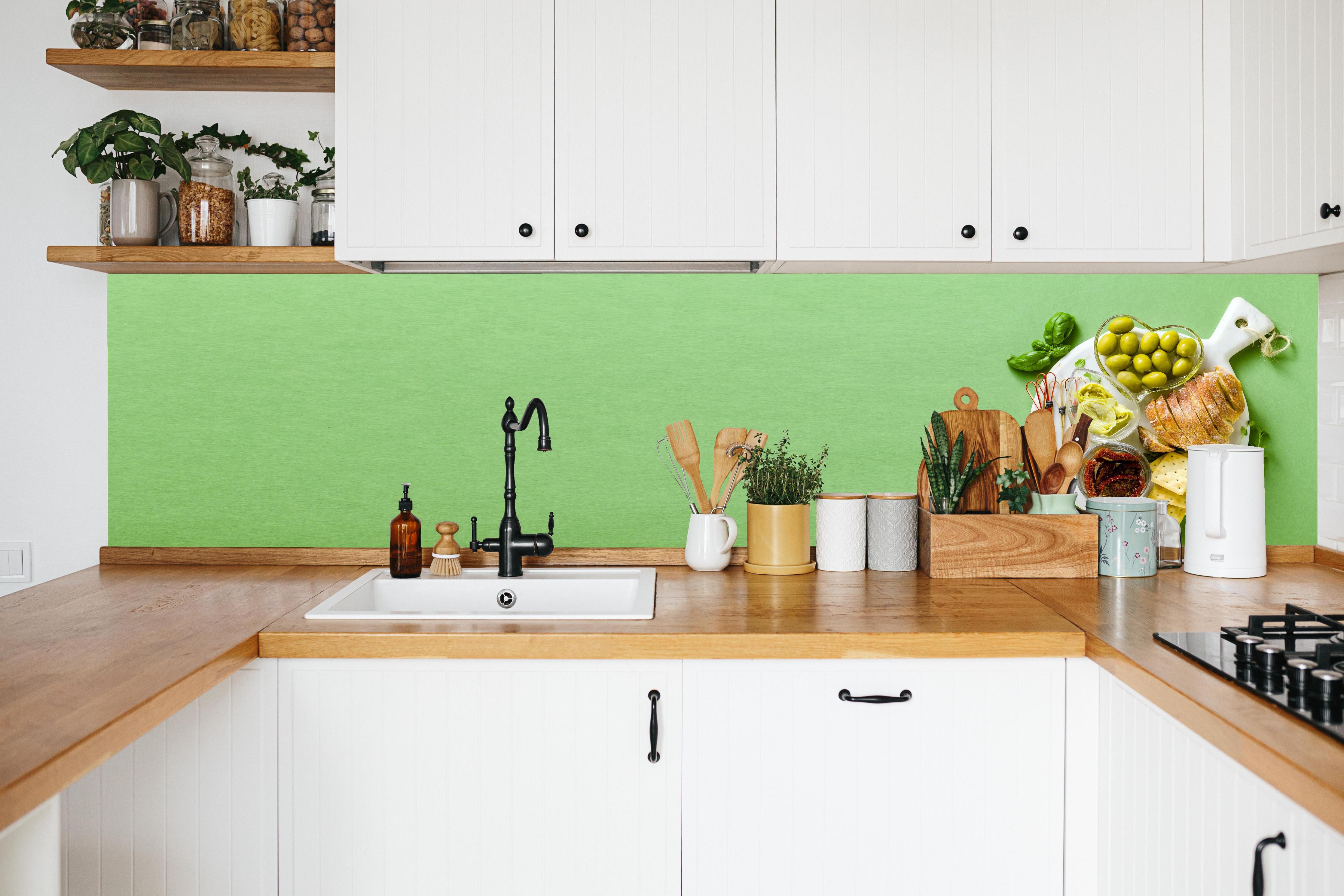 Küche - Grüne Küchenrückwand mit Oliven in weißer Küche hinter Gewürzen und Kochlöffeln aus Holz