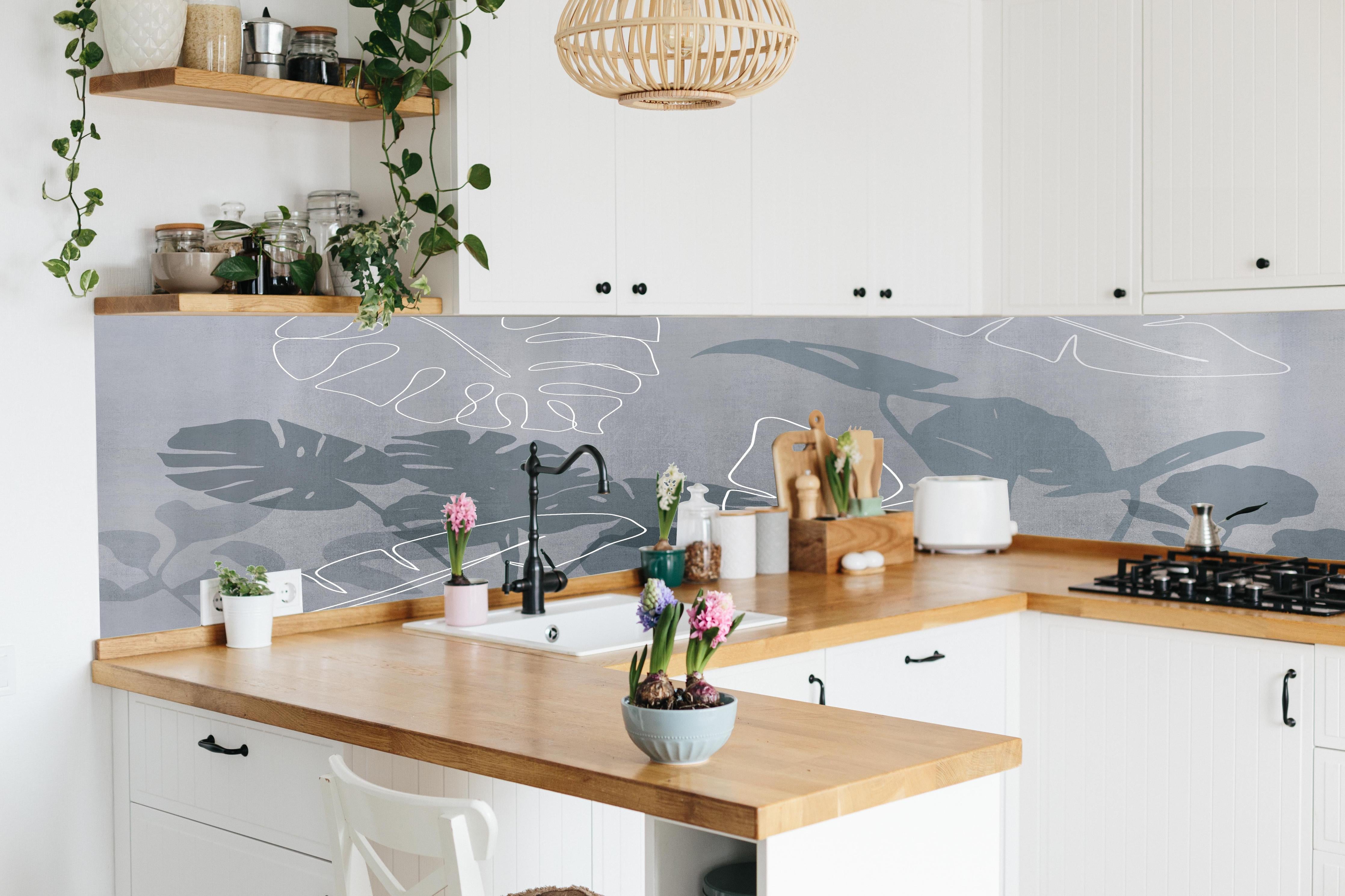 Küche - Abstrakte Blätter hinter weißen Hochglanz-Küchenregalen und schwarzem Wasserhahn