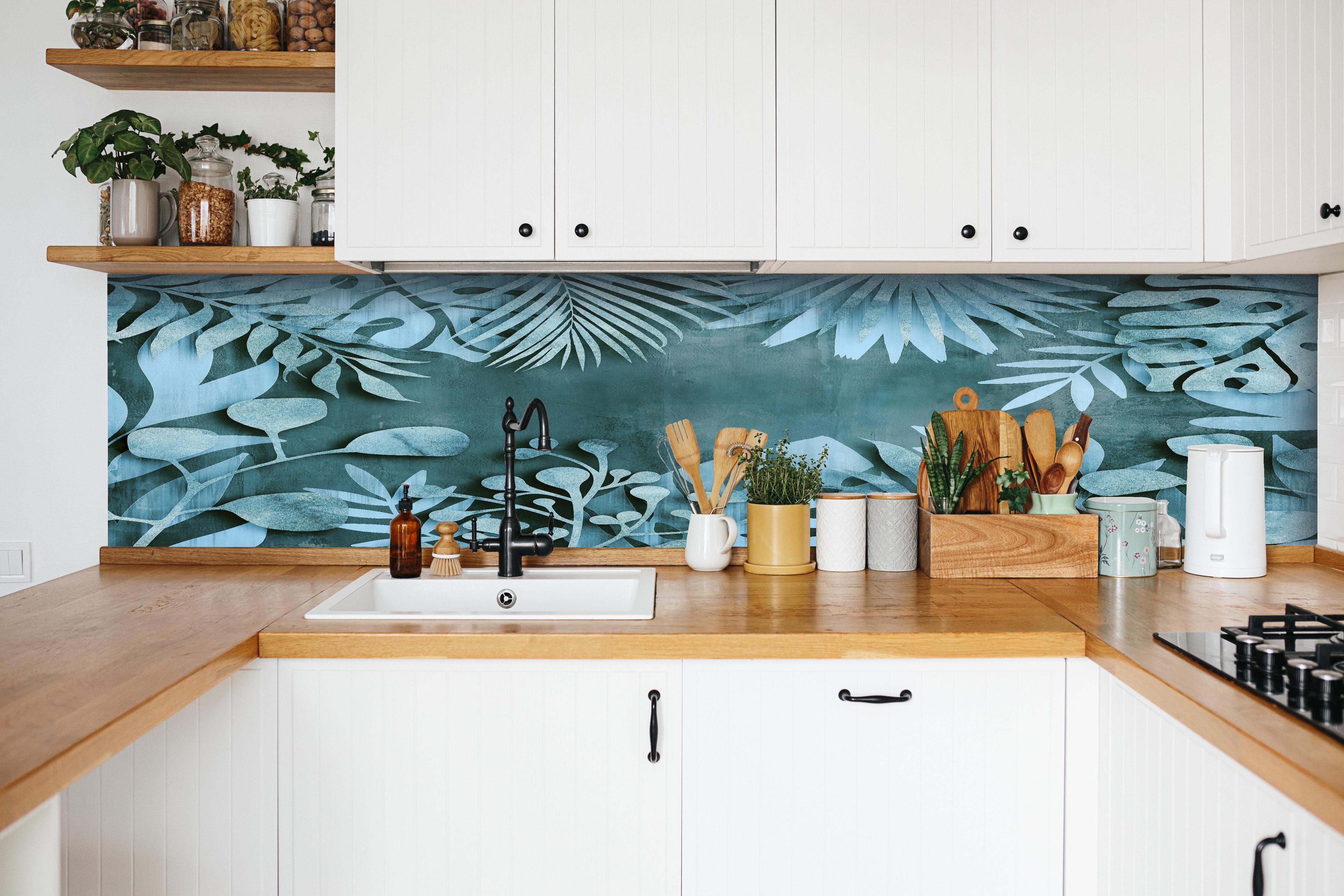 Küche - Abstrakte Blatt-Strukturen in Türkisblau hinter weißen Hochglanz-Küchenregalen und schwarzem Wasserhahn