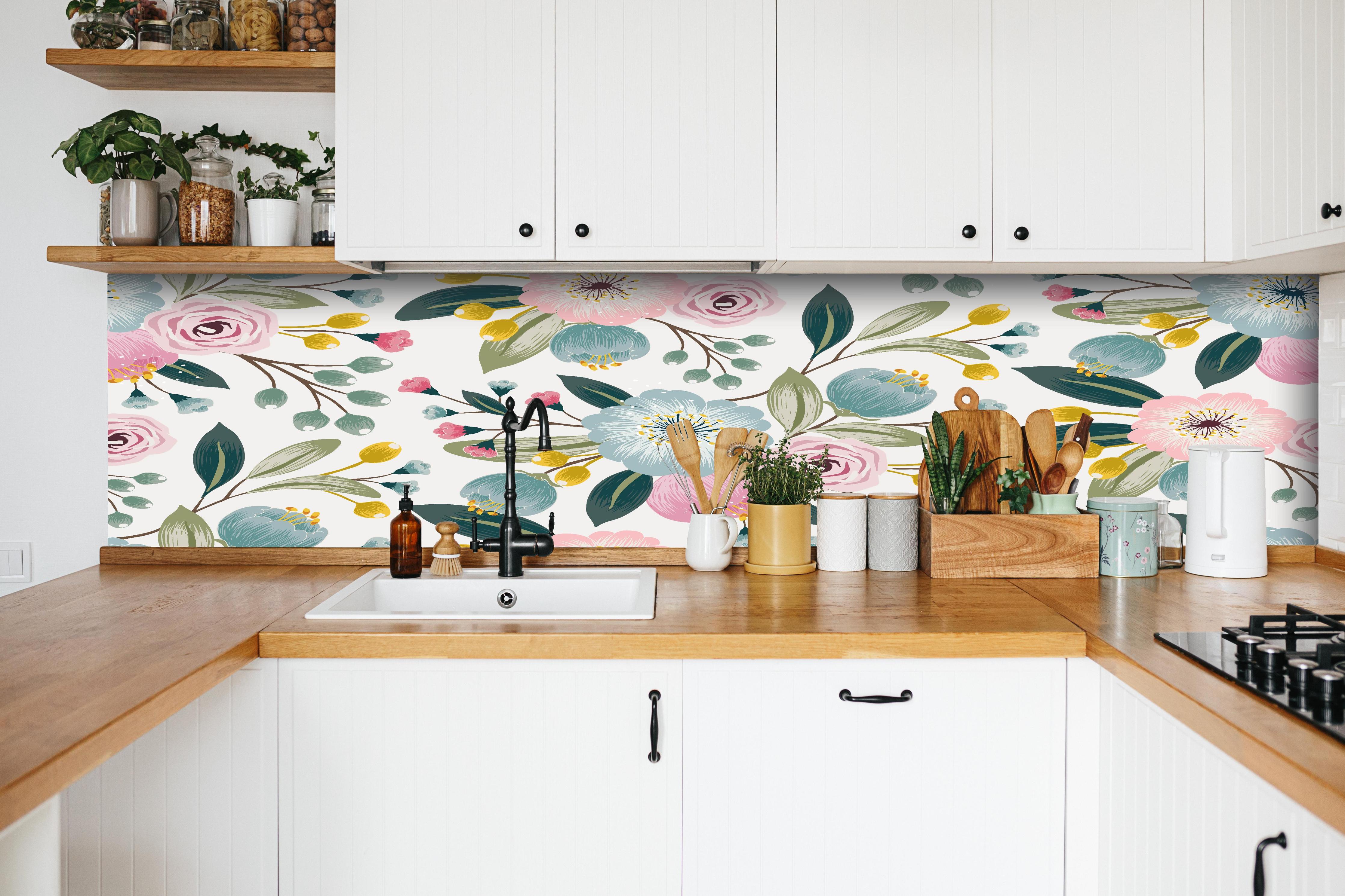 Küche - Abstrakte Blumenmuster in Rosa und Hellblau hinter weißen Hochglanz-Küchenregalen und schwarzem Wasserhahn