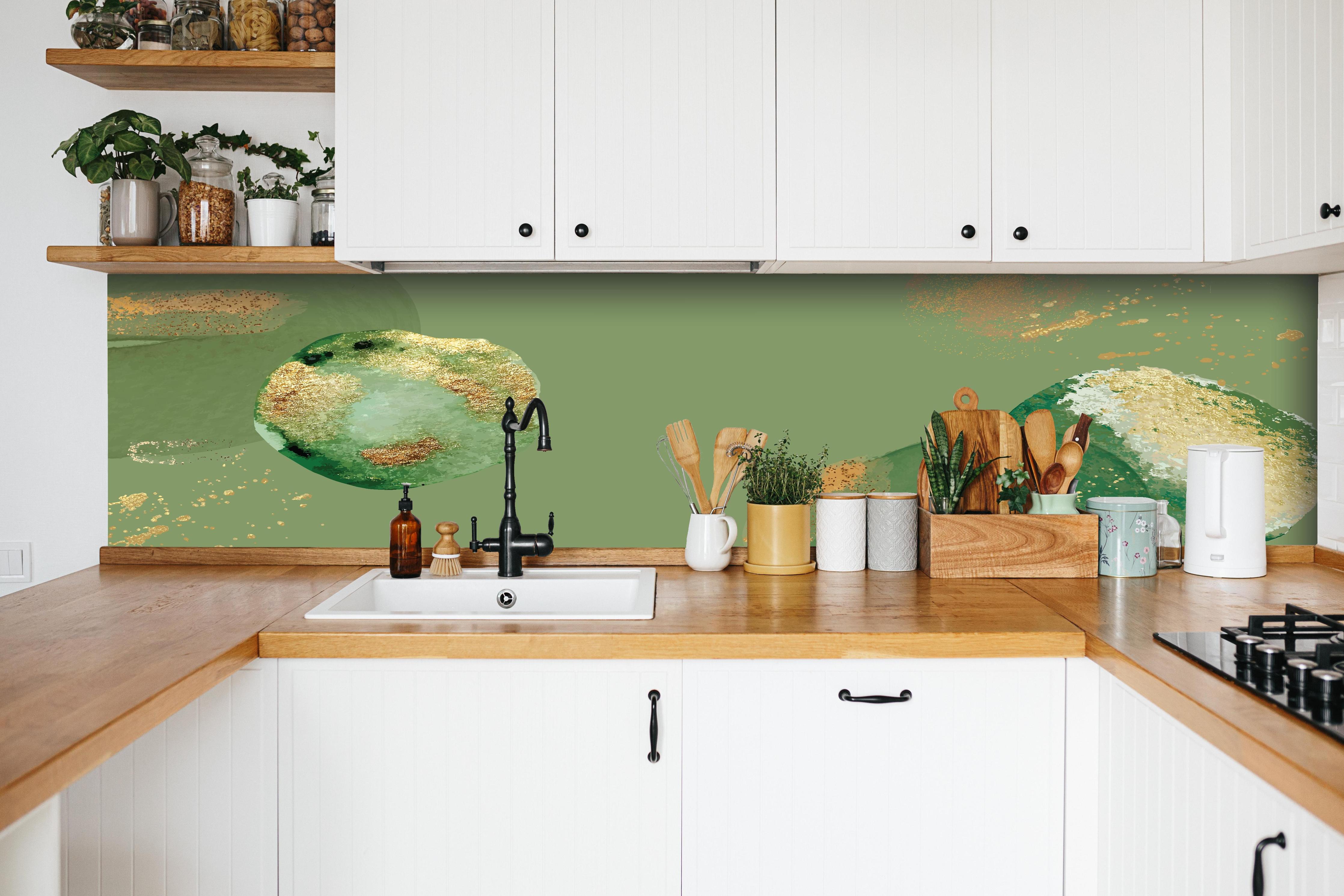 Küche - Abstraktes Design mit Grün und Goldtönen hinter weißen Hochglanz-Küchenregalen und schwarzem Wasserhahn