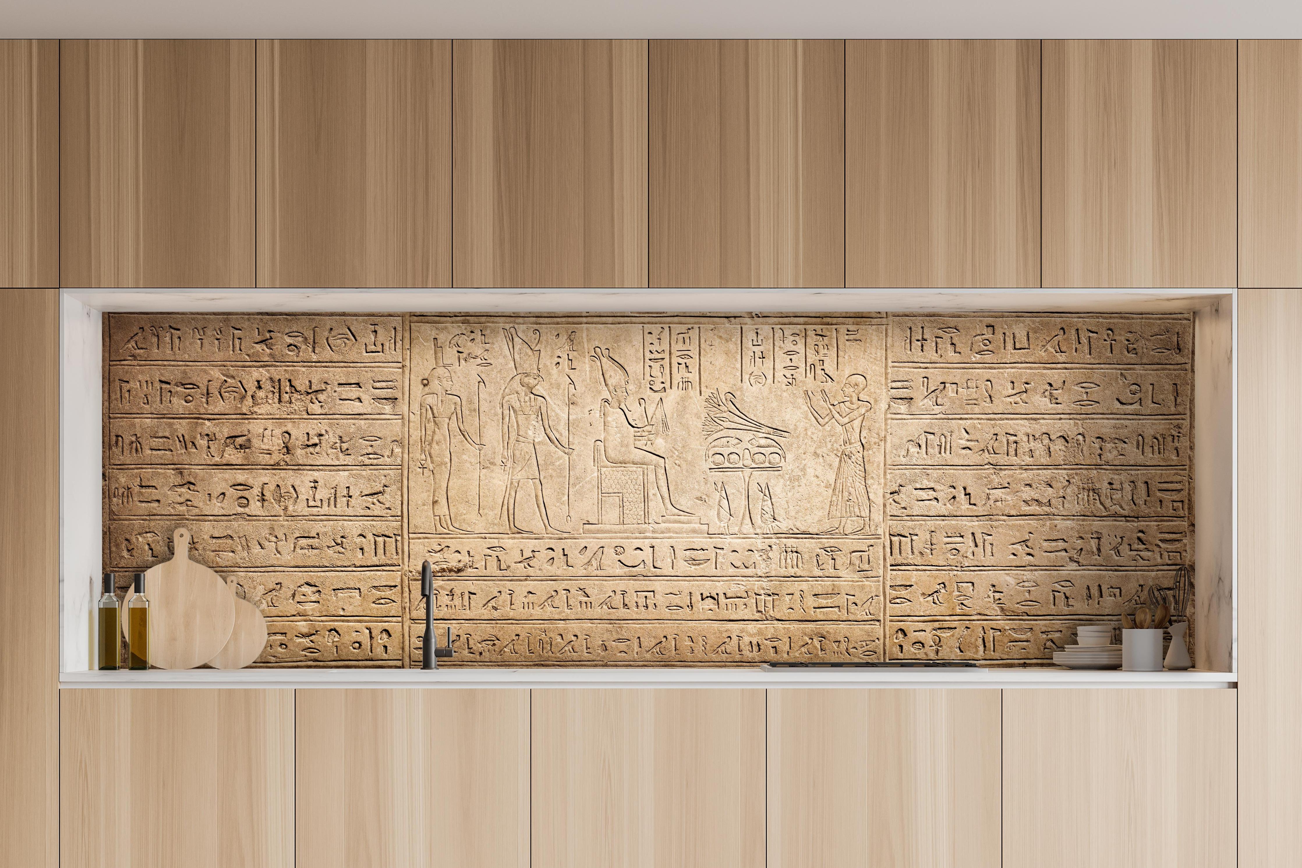Küche - Ägyptische Hieroglyphen auf Sandstein hinter weißen Hochglanz-Küchenregalen und schwarzem Wasserhahn