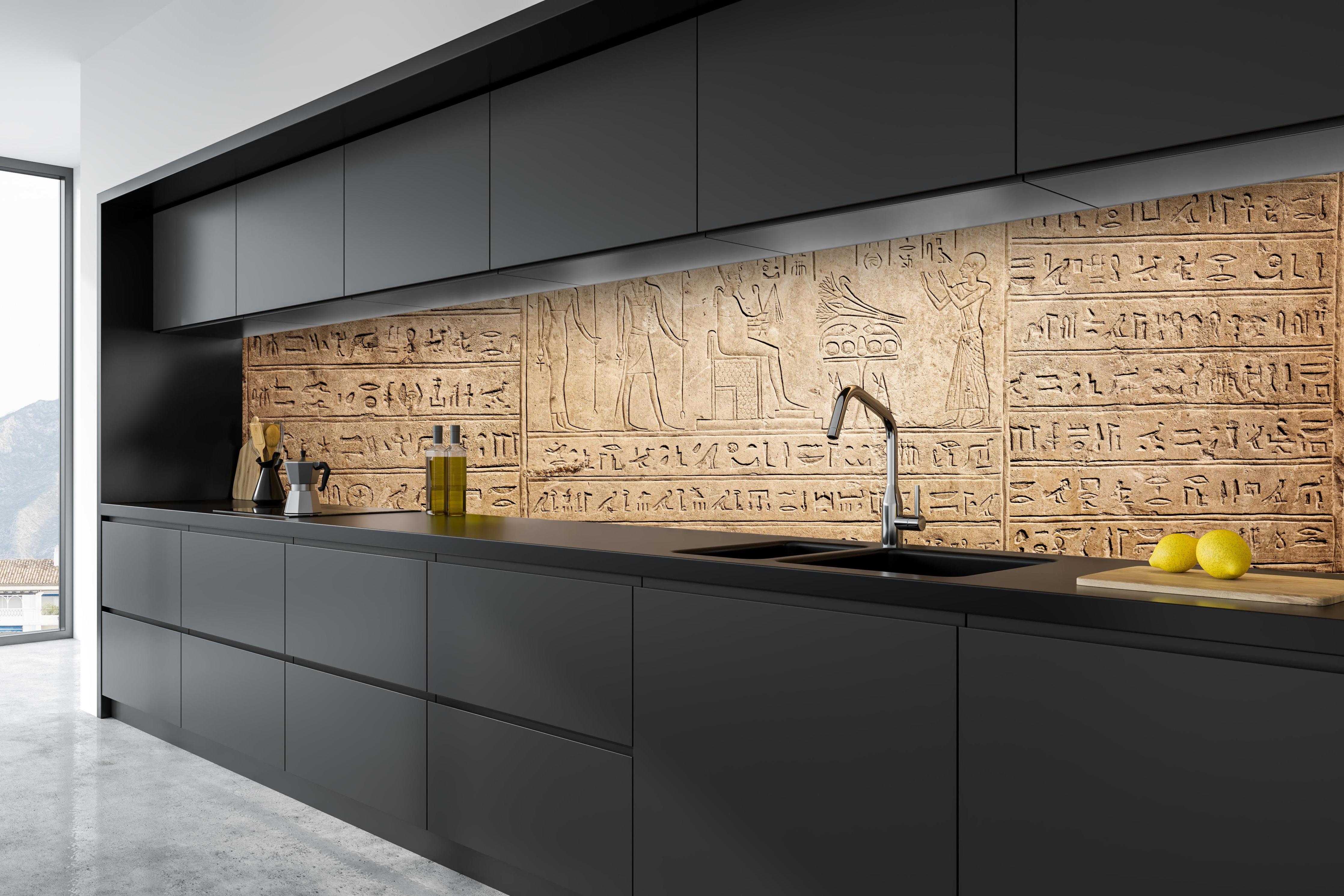 Küche - Ägyptische Hieroglyphen auf Sandstein hinter weißen Hochglanz-Küchenregalen und schwarzem Wasserhahn
