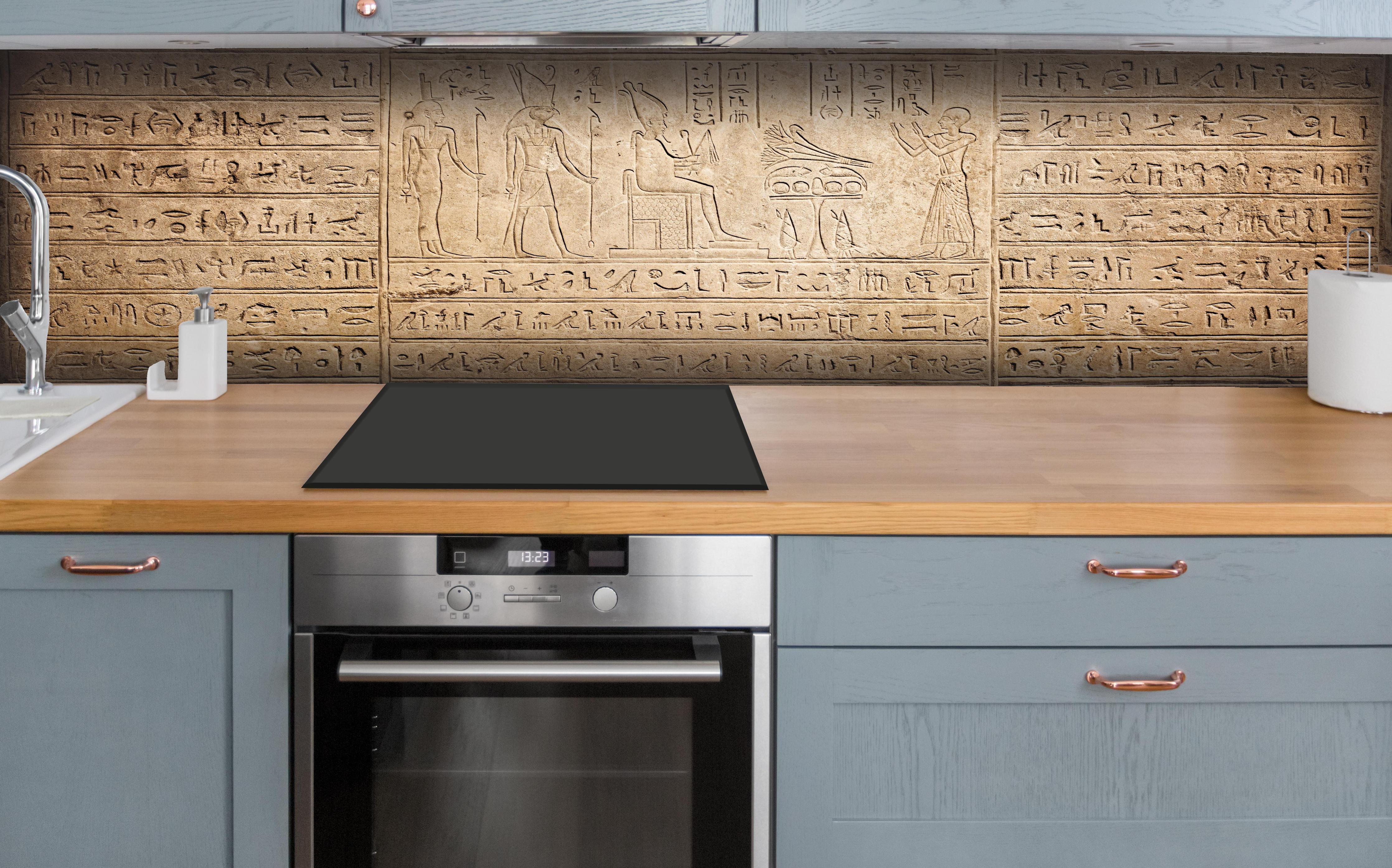 Küche - Ägyptische Hieroglyphen auf Sandstein hinter weißen Hochglanz-Küchenregalen und schwarzem Wasserhahn