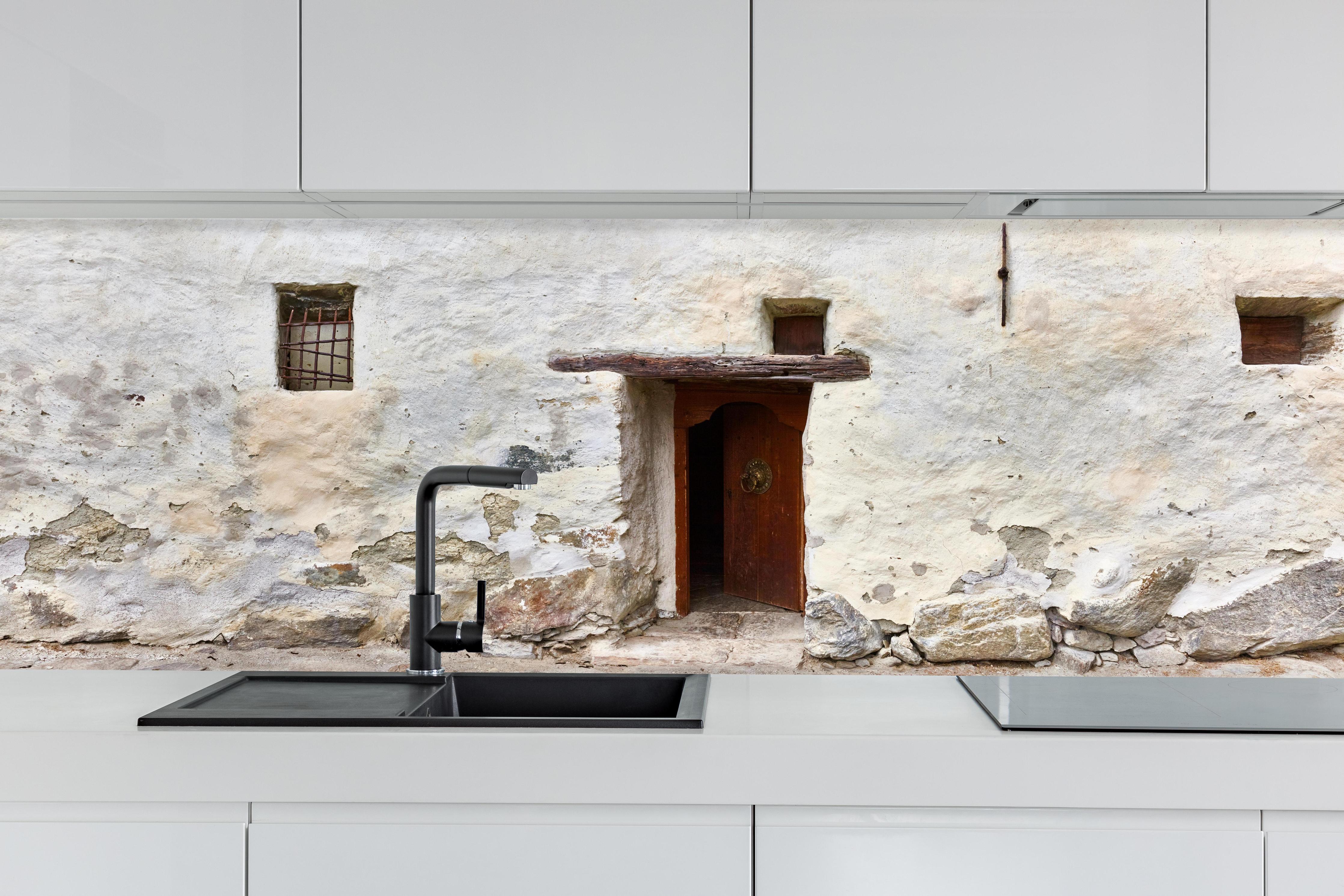 Küche - Alter Türeingang in Südtirol hinter weißen Hochglanz-Küchenregalen und schwarzem Wasserhahn