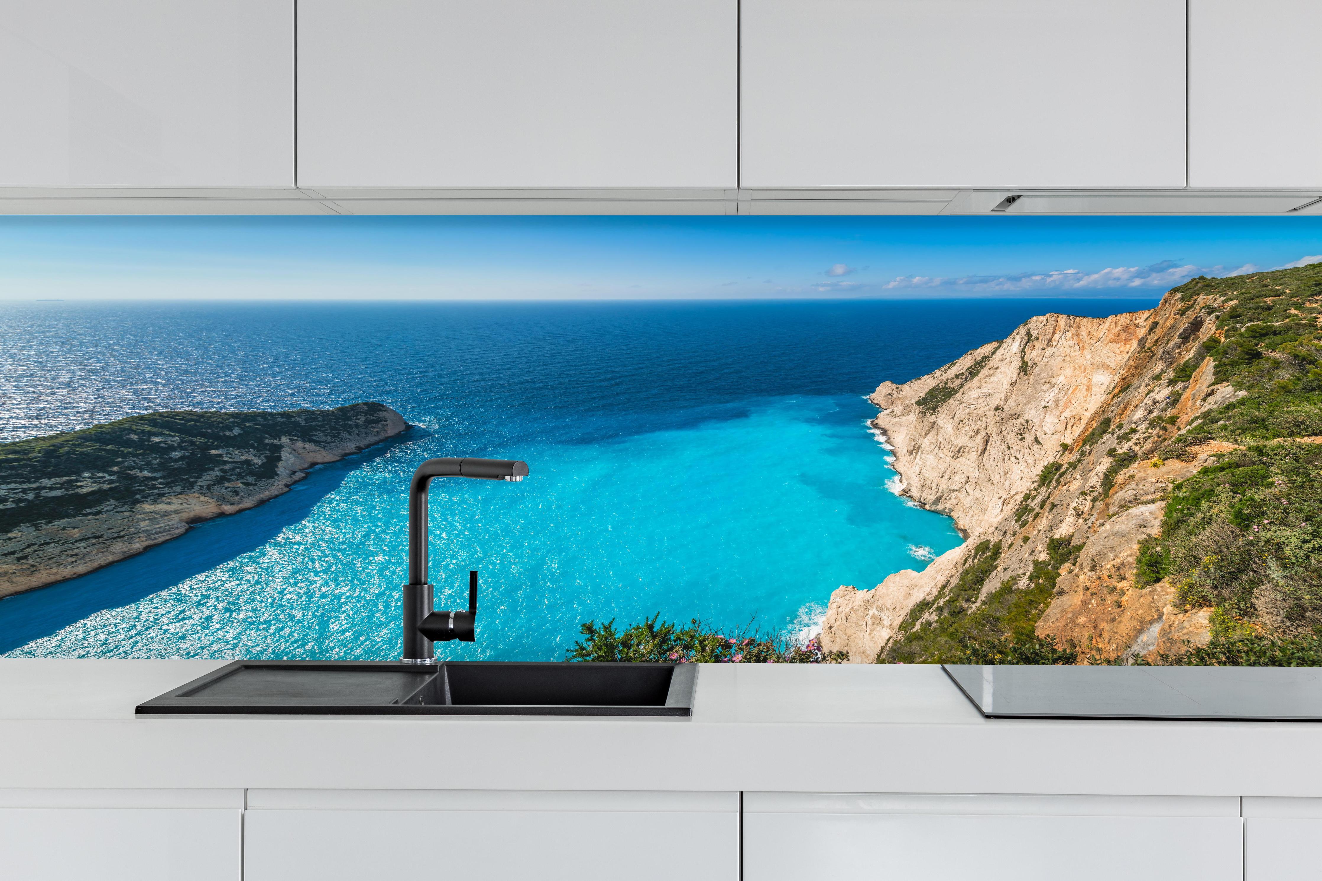Küche - Atemberaubende Aussicht auf türkisblaue Küstenlandschaft hinter weißen Hochglanz-Küchenregalen und schwarzem Wasserhahn