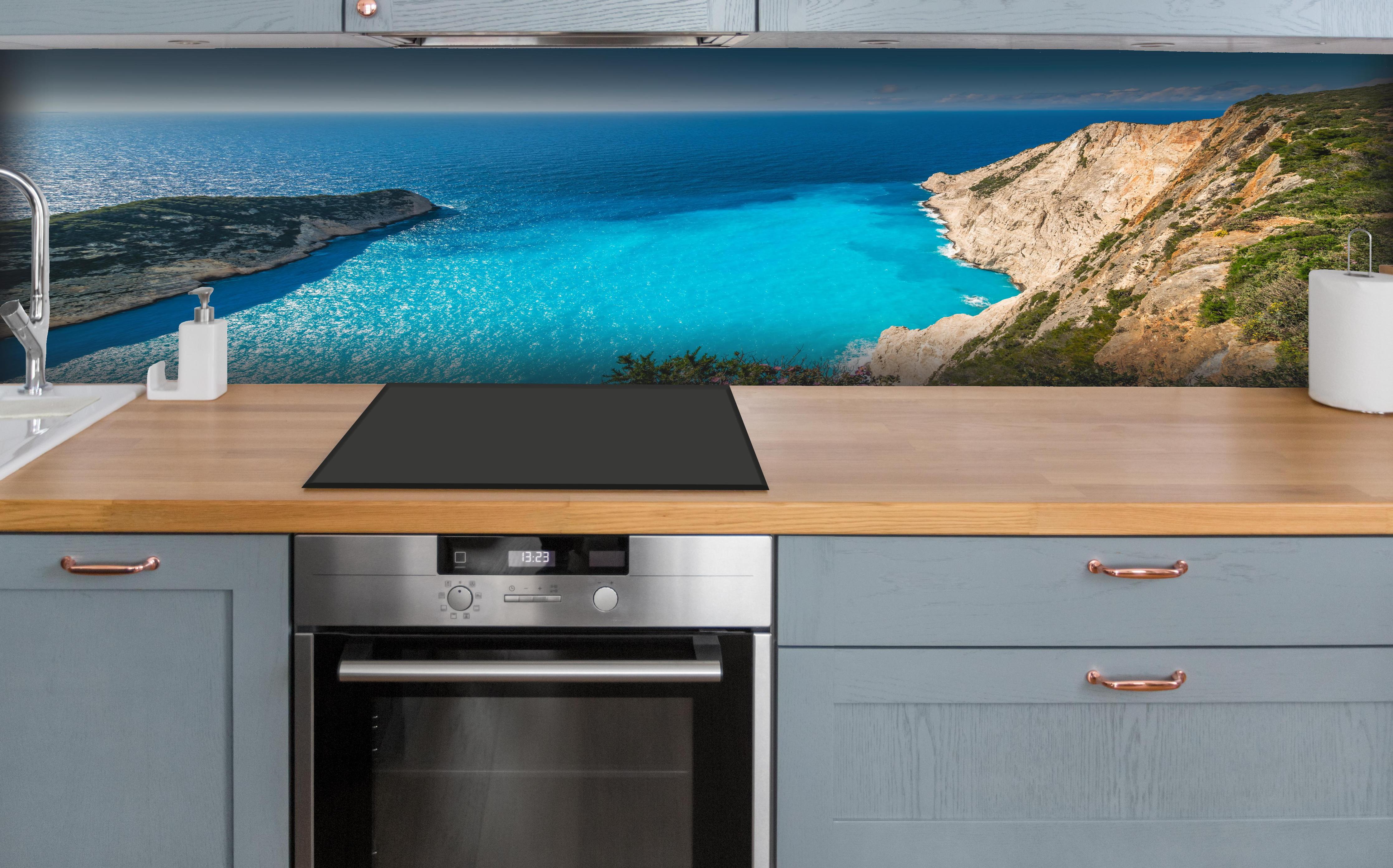 Küche - Atemberaubende Aussicht auf türkisblaue Küstenlandschaft hinter weißen Hochglanz-Küchenregalen und schwarzem Wasserhahn