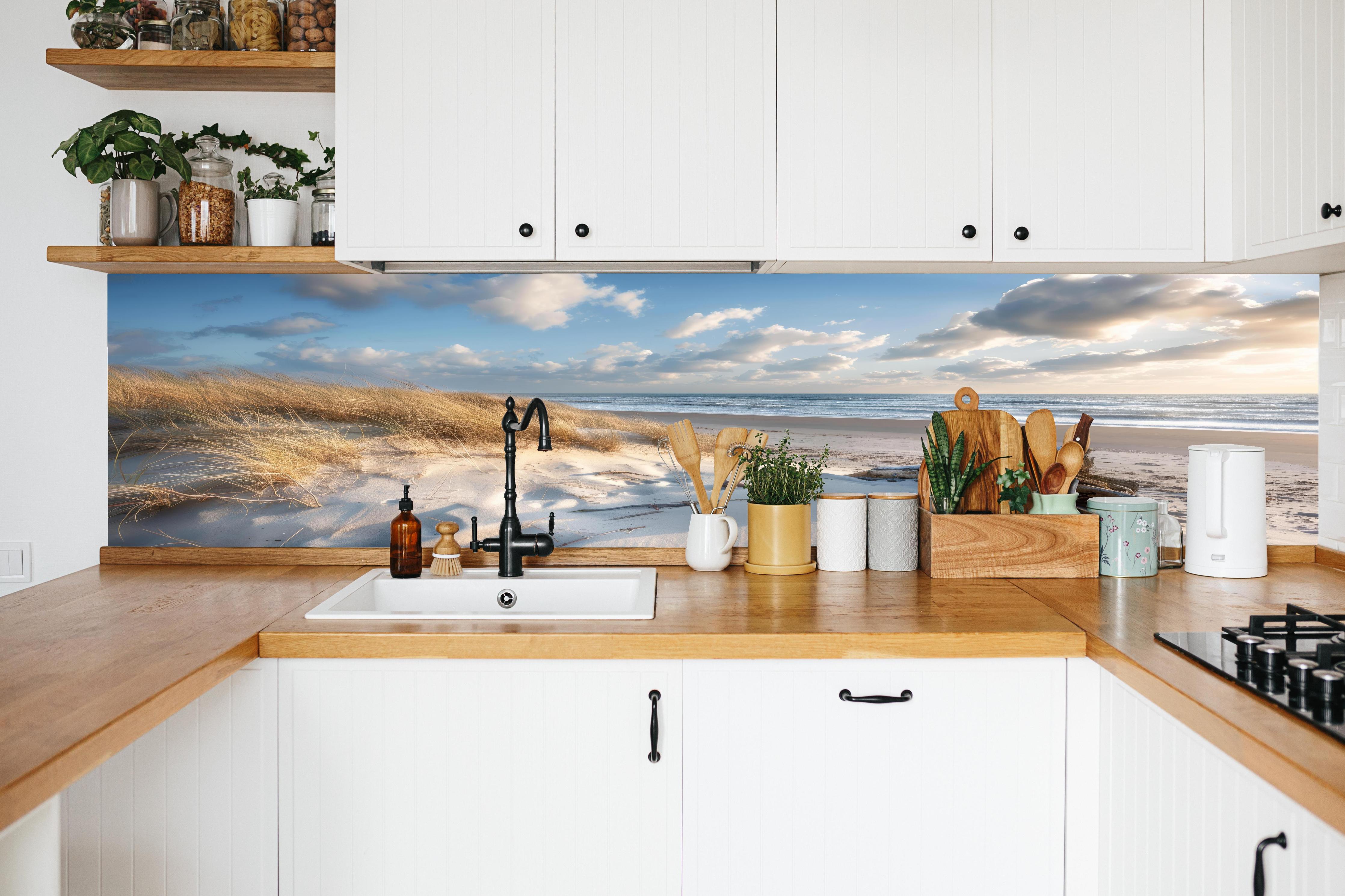 Küche - Atemberaubender Strand mit feinem Sand und grauen Wolkenformationen hinter weißen Hochglanz-Küchenregalen und schwarzem Wasserhahn