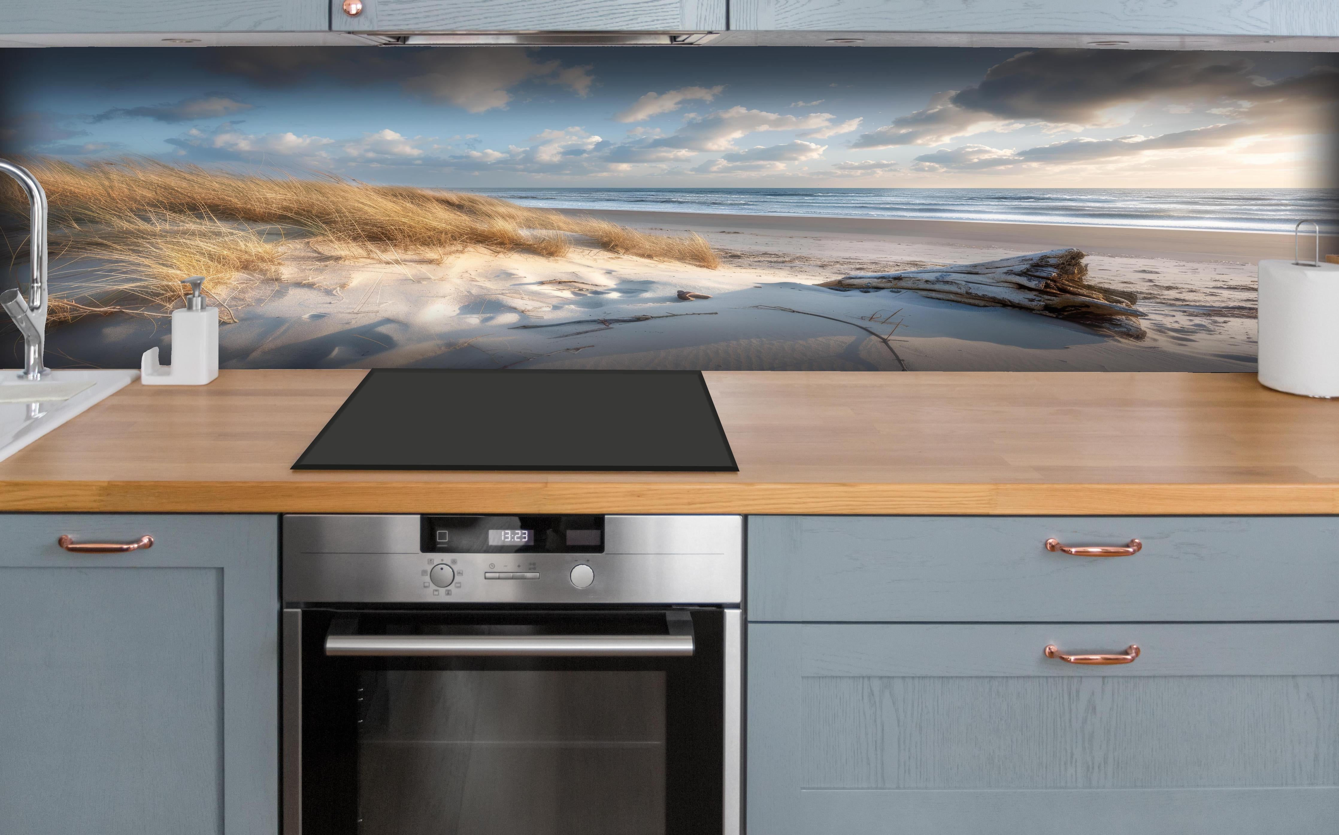 Küche - Atemberaubender Strand mit feinem Sand und grauen Wolkenformationen hinter weißen Hochglanz-Küchenregalen und schwarzem Wasserhahn