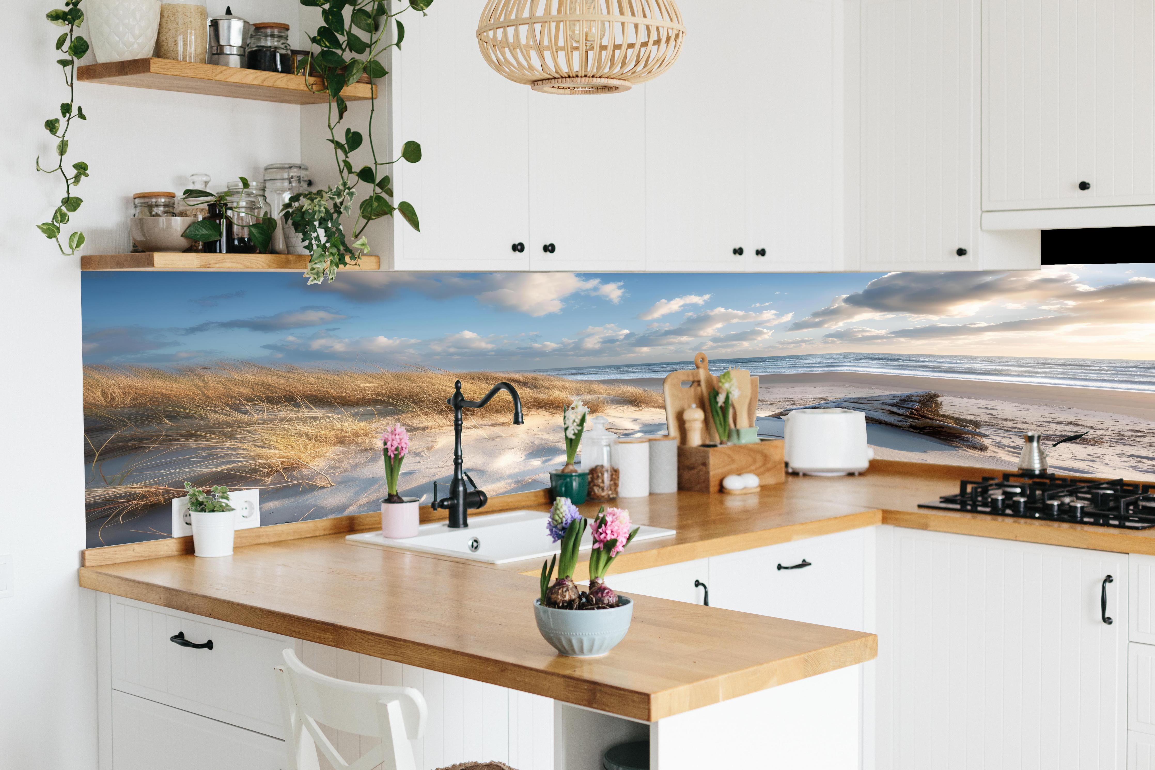 Küche - Atemberaubender Strand mit feinem Sand und grauen Wolkenformationen hinter weißen Hochglanz-Küchenregalen und schwarzem Wasserhahn