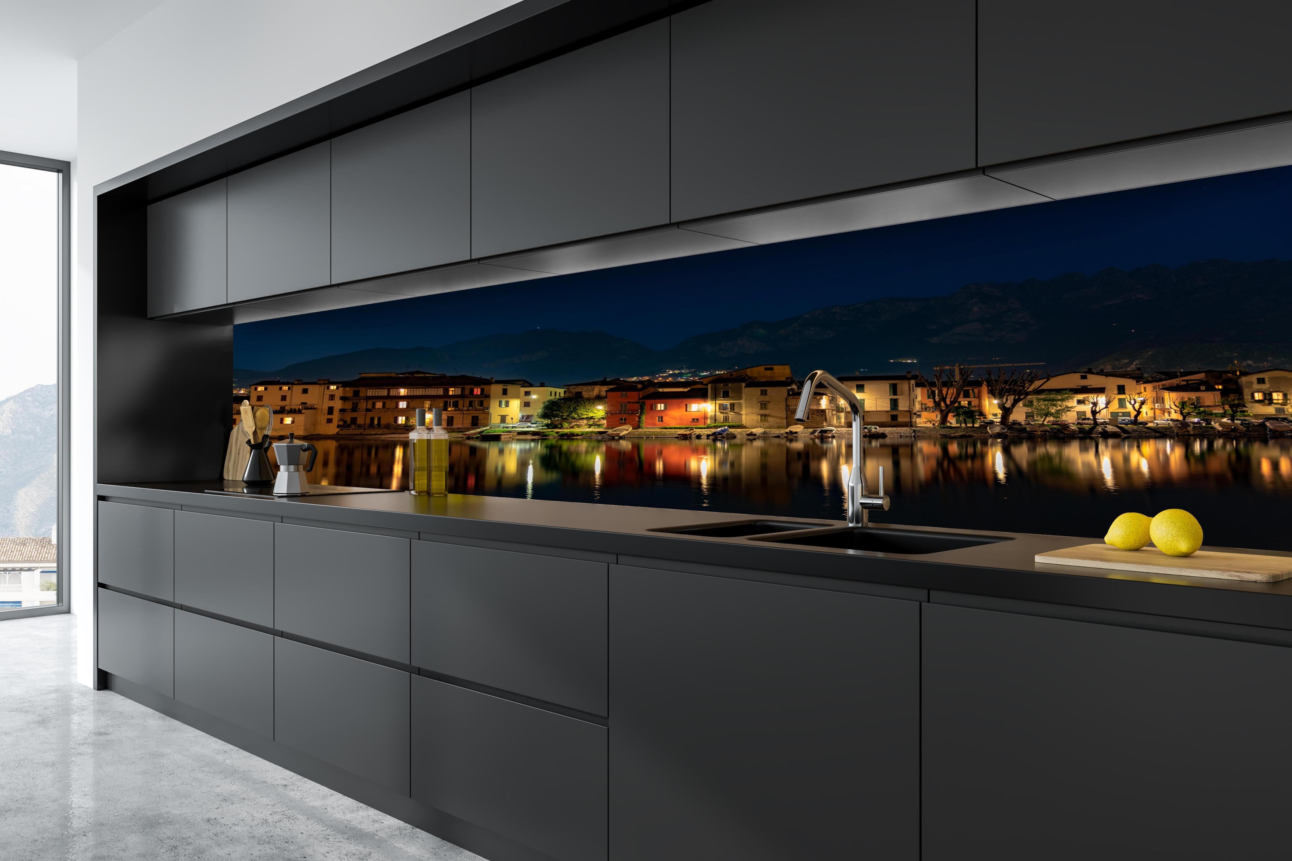 Küche - Beleuchtete Seelandschaft bei Nacht hinter weißen Hochglanz-Küchenregalen und schwarzem Wasserhahn