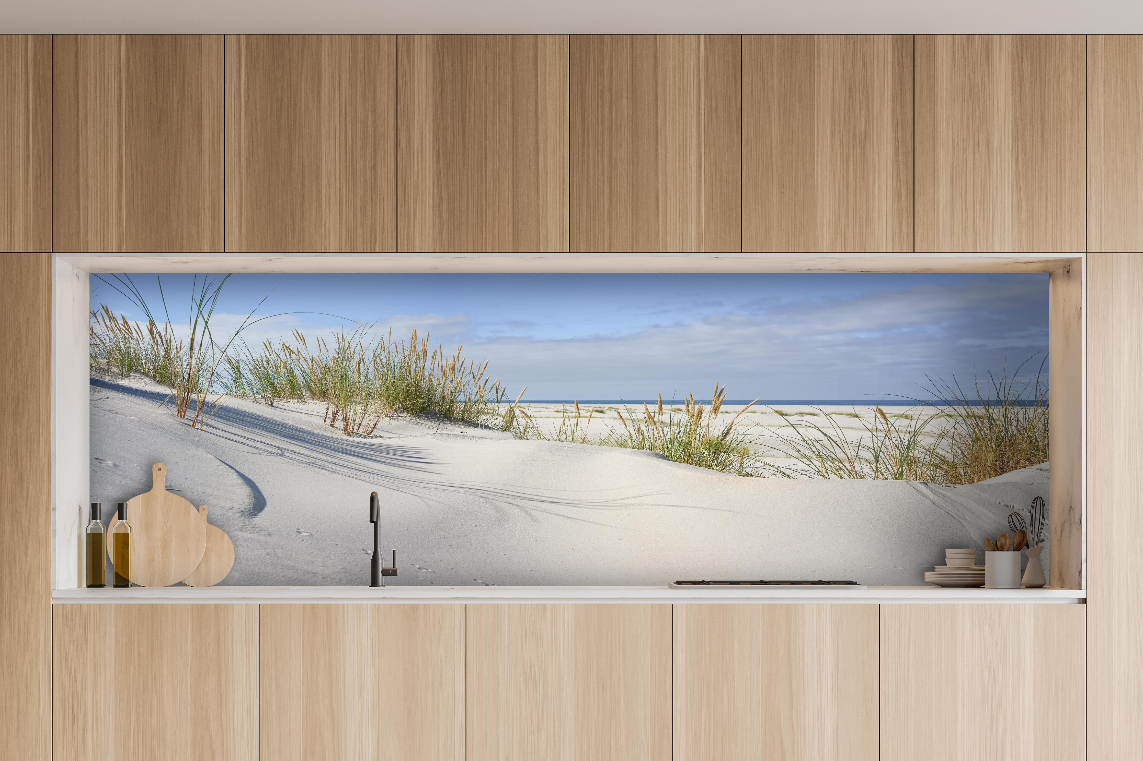 Küche - Beruhigende weiße Dünenlandschaft mit sanften Gräsern am Ozean hinter weißen Hochglanz-Küchenregalen und schwarzem Wasserhahn