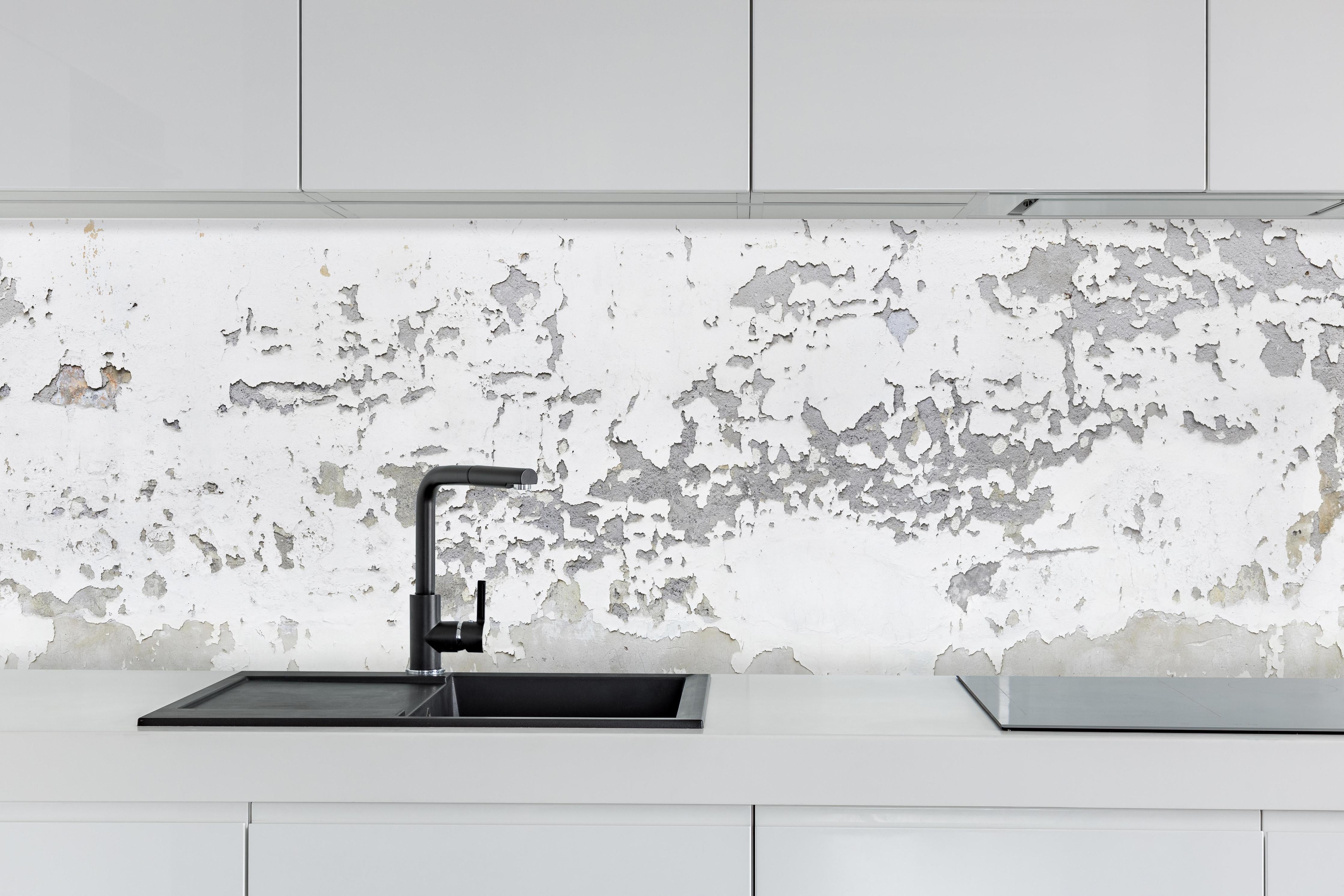 Küche - Beschädigte Wandstruktur hinter weißen Hochglanz-Küchenregalen und schwarzem Wasserhahn