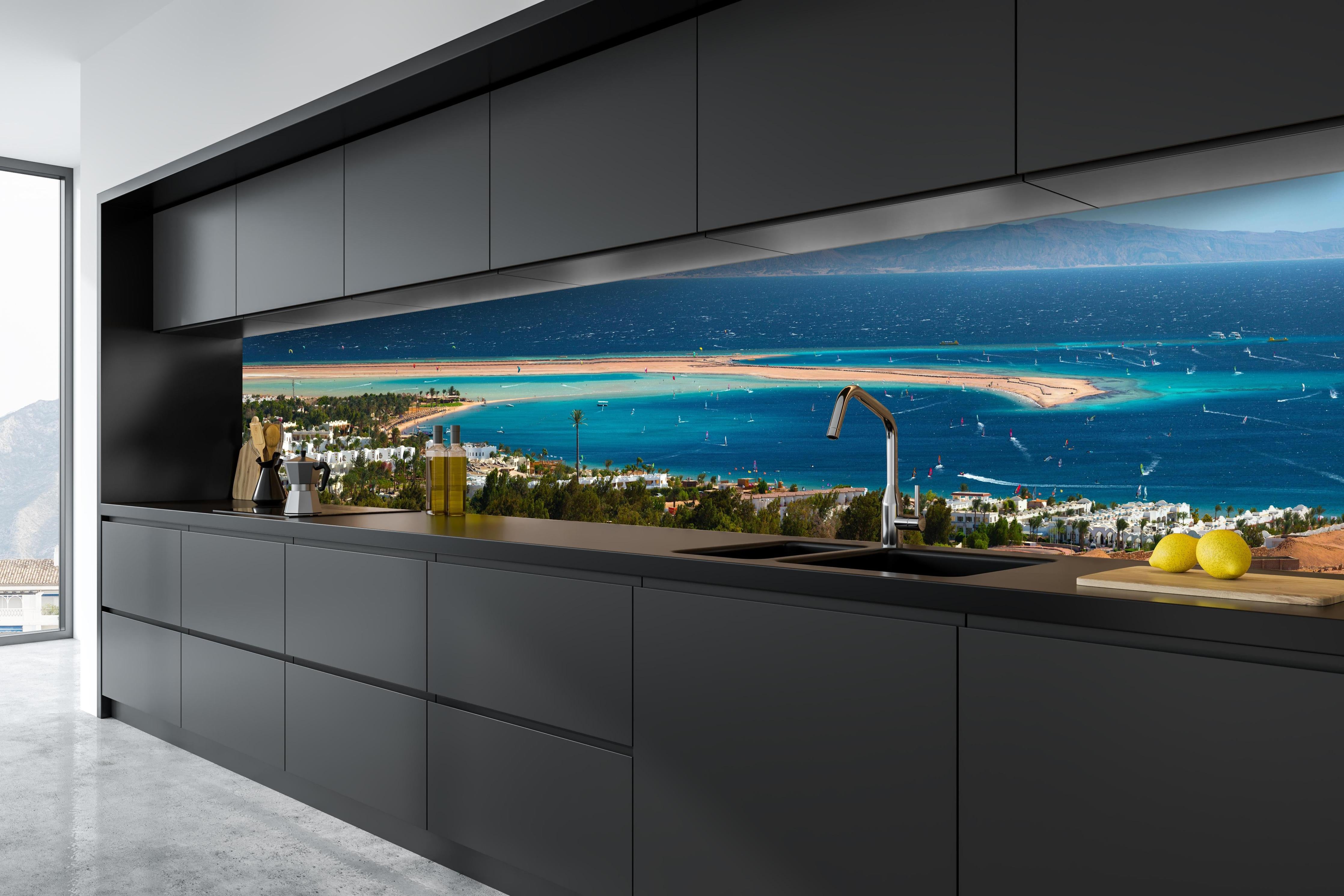 Küche - Blaue Lagune am Meer Panoramabild hinter weißen Hochglanz-Küchenregalen und schwarzem Wasserhahn