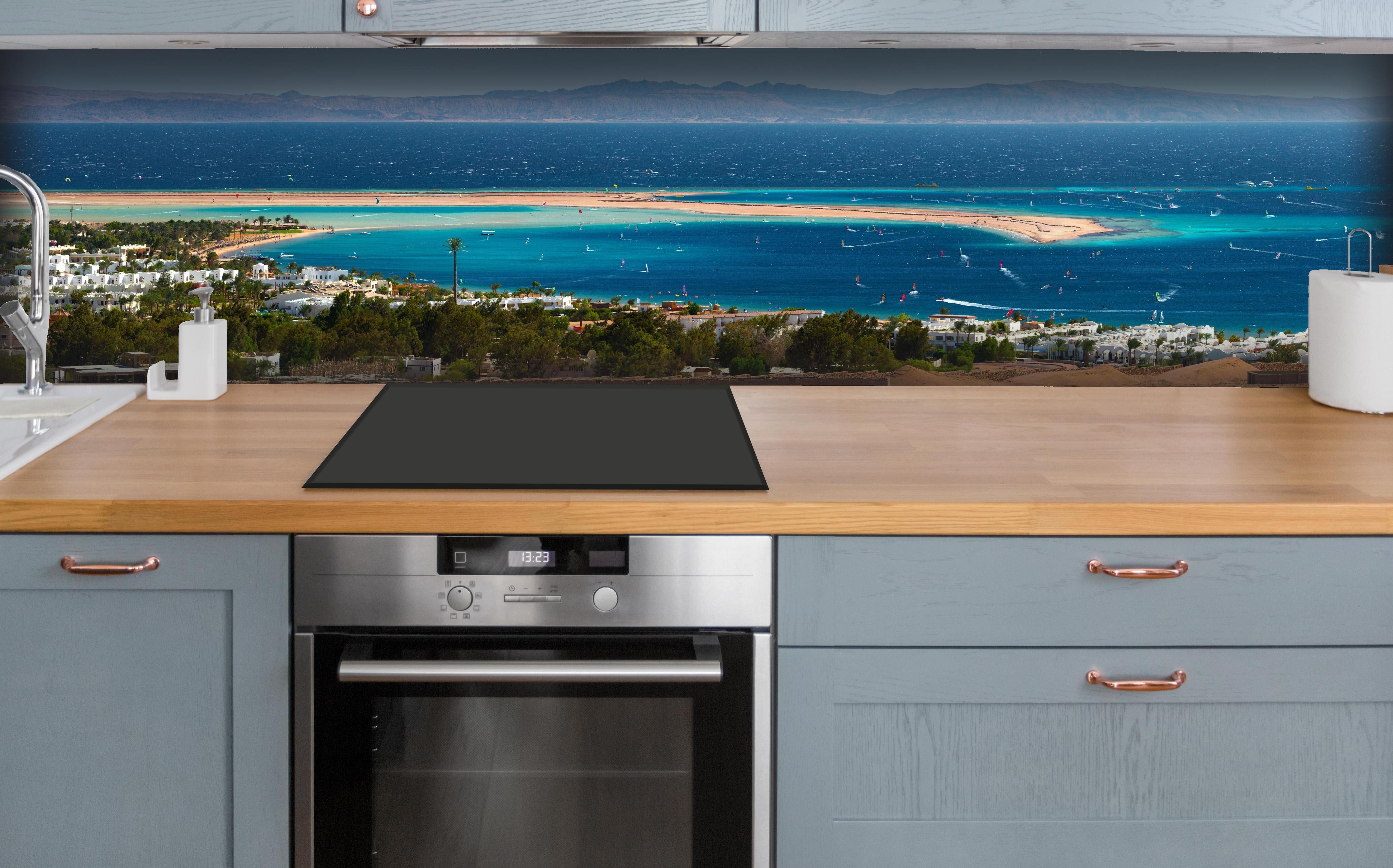 Küche - Blaue Lagune am Meer Panoramabild hinter weißen Hochglanz-Küchenregalen und schwarzem Wasserhahn