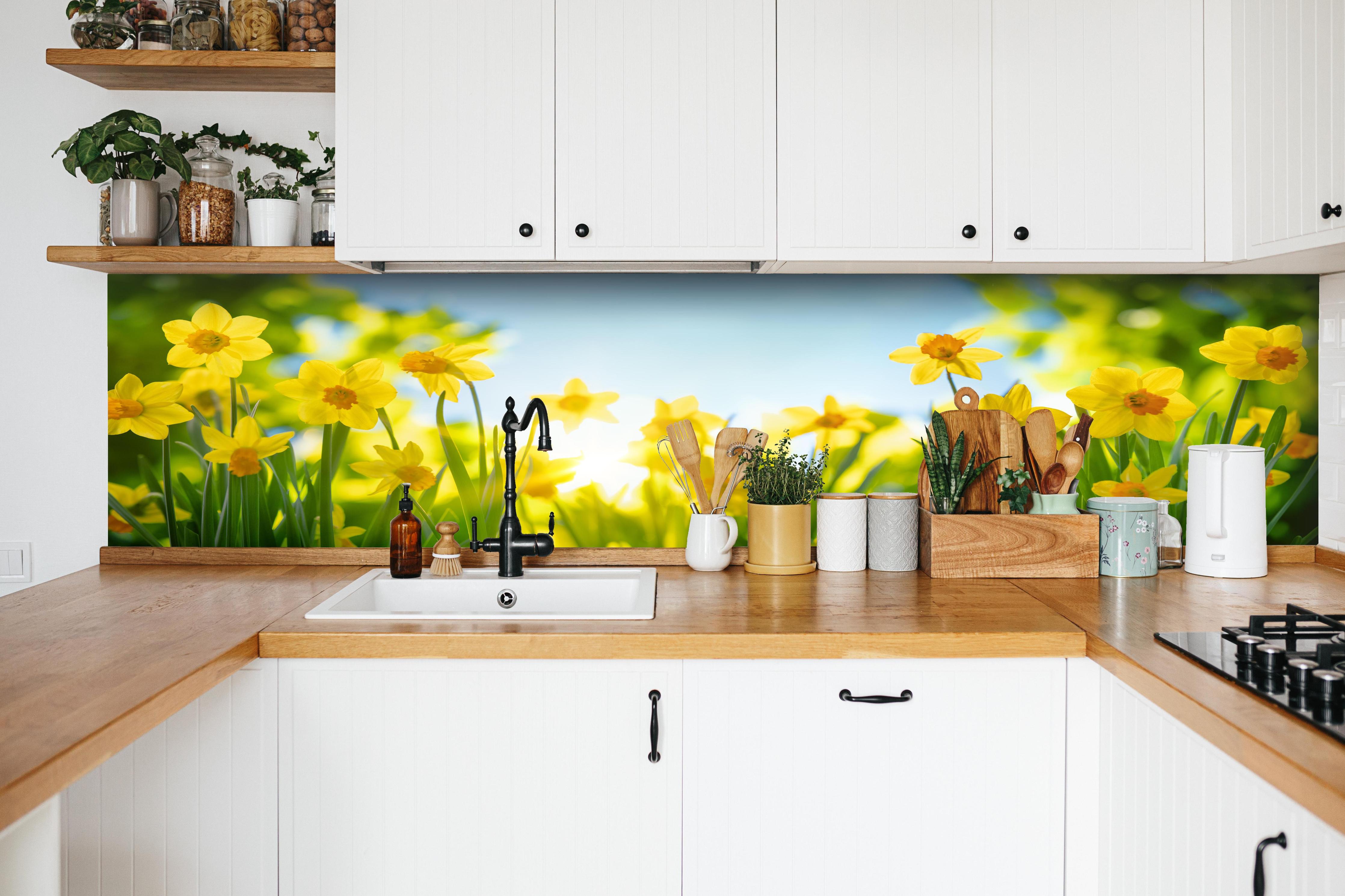 Küche - Blühende Frühlings-Narzissen hinter weißen Hochglanz-Küchenregalen und schwarzem Wasserhahn