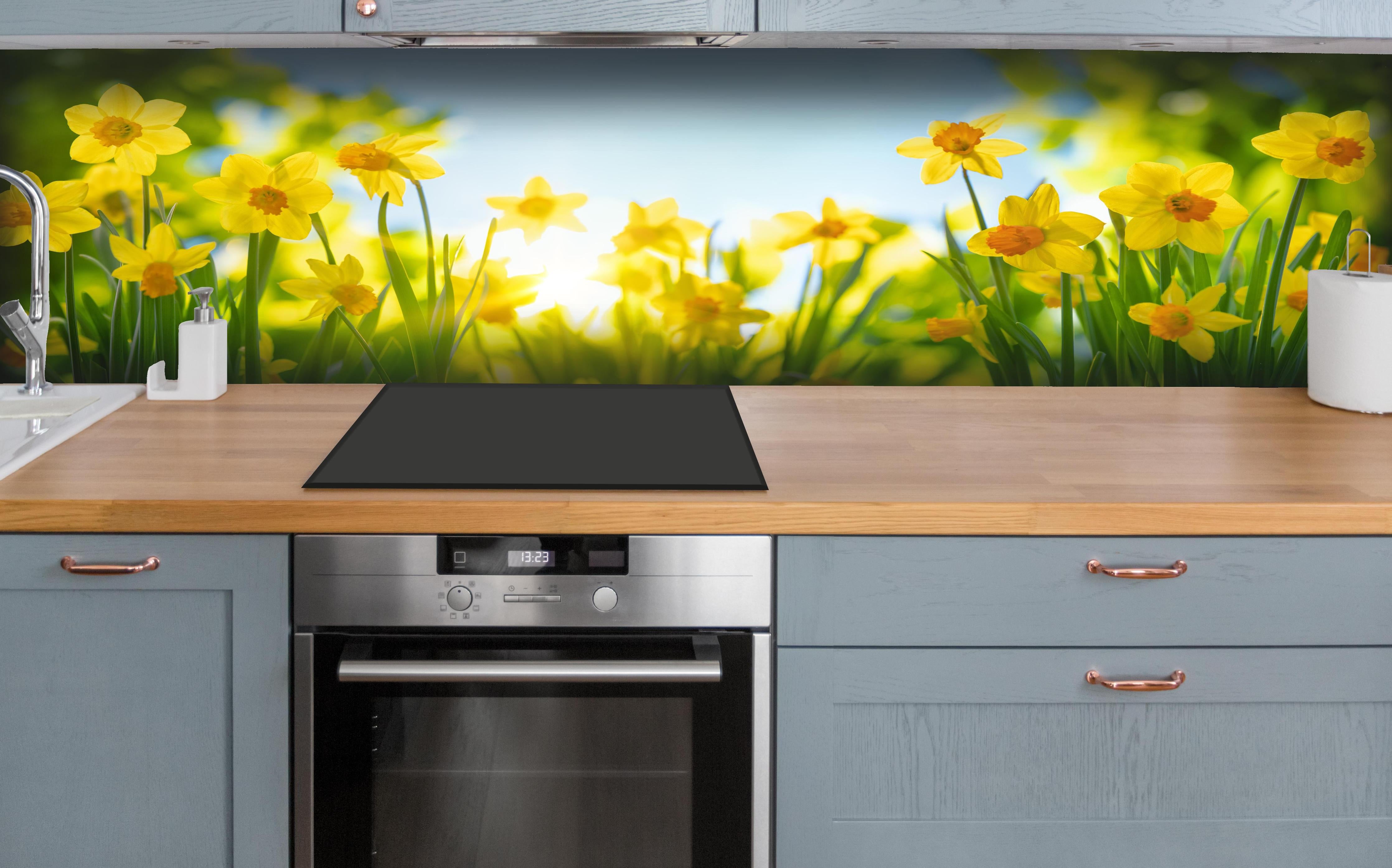 Küche - Blühende Frühlings-Narzissen hinter weißen Hochglanz-Küchenregalen und schwarzem Wasserhahn