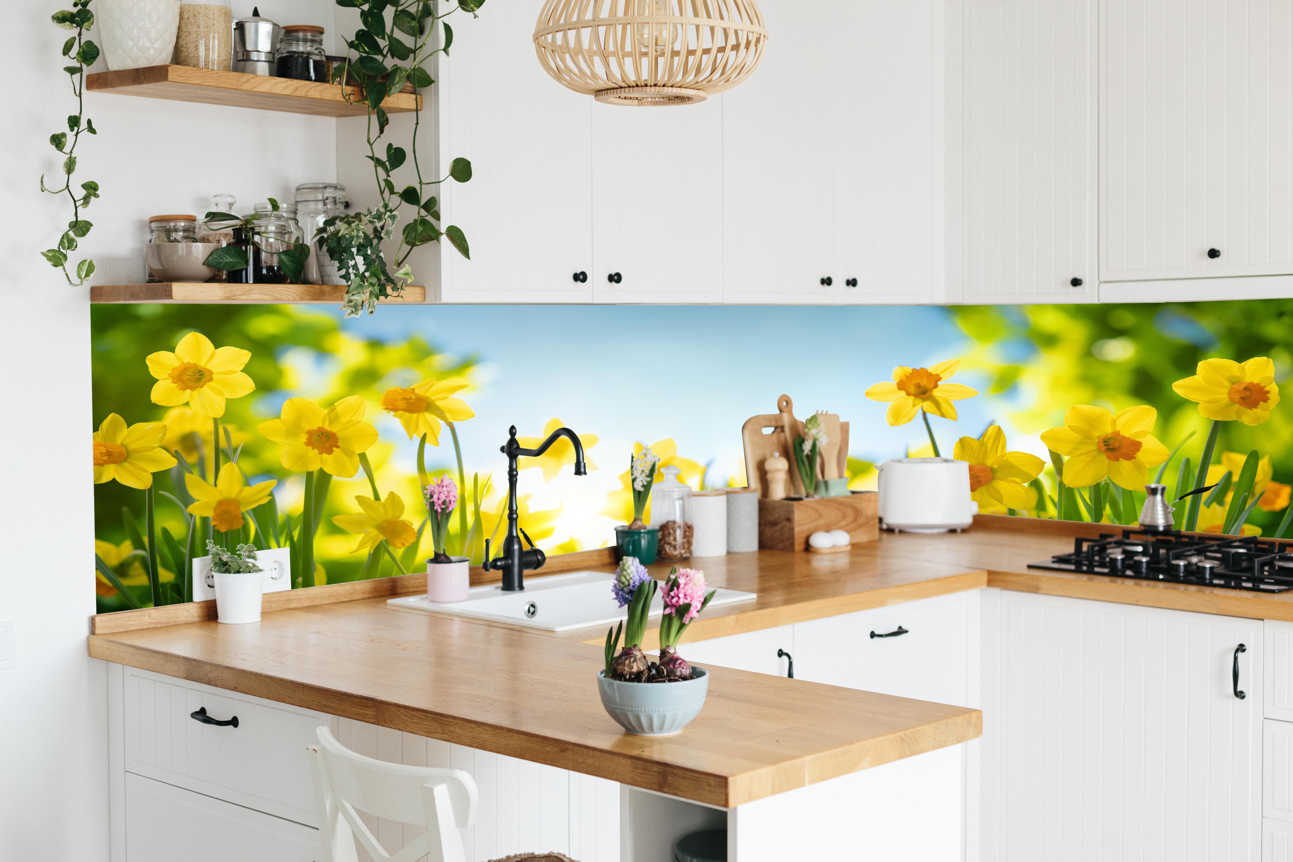 Küche - Blühende Frühlings-Narzissen hinter weißen Hochglanz-Küchenregalen und schwarzem Wasserhahn