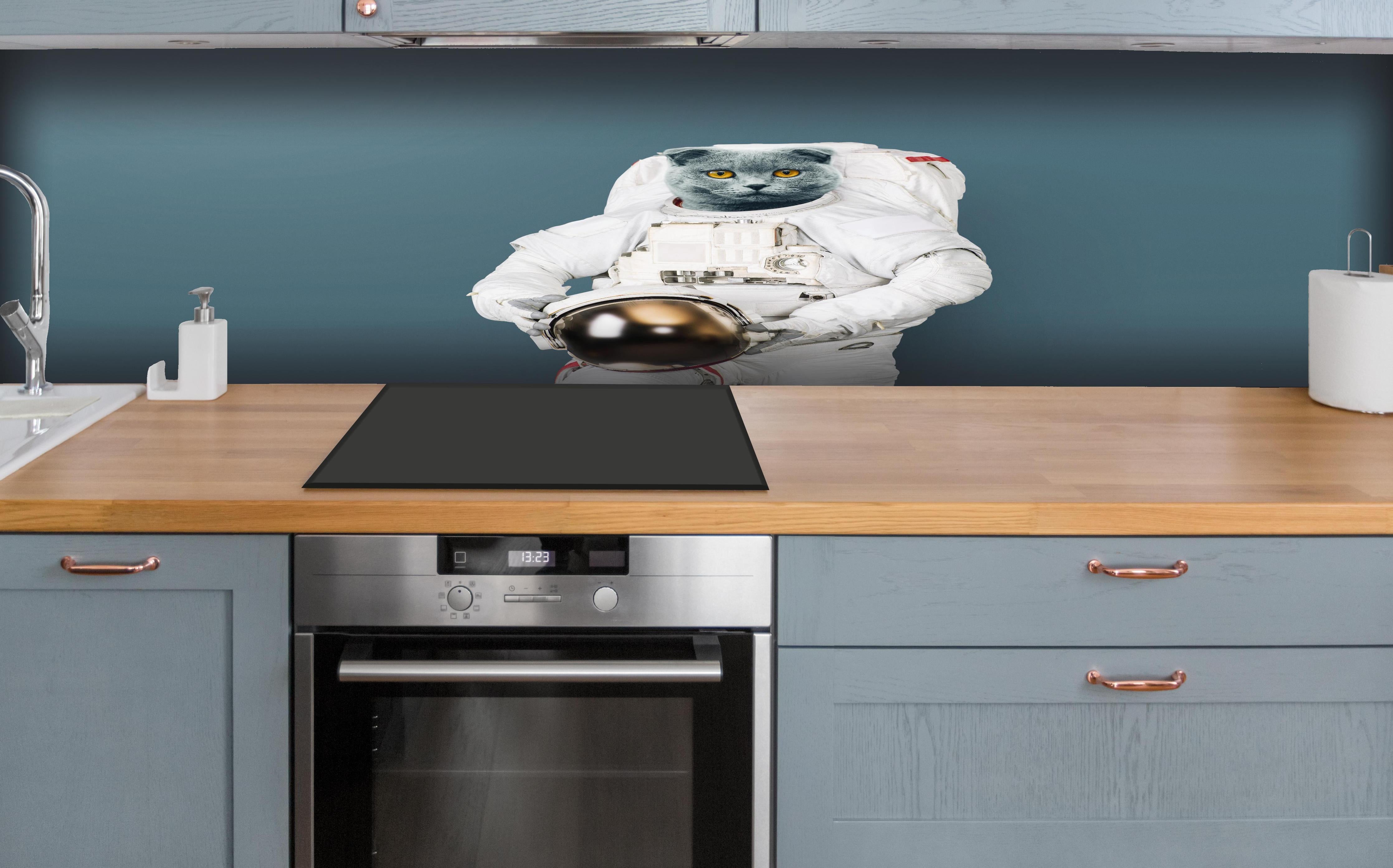 Küche - Britischer Katzen-Astronaut mit Helm hinter weißen Hochglanz-Küchenregalen und schwarzem Wasserhahn