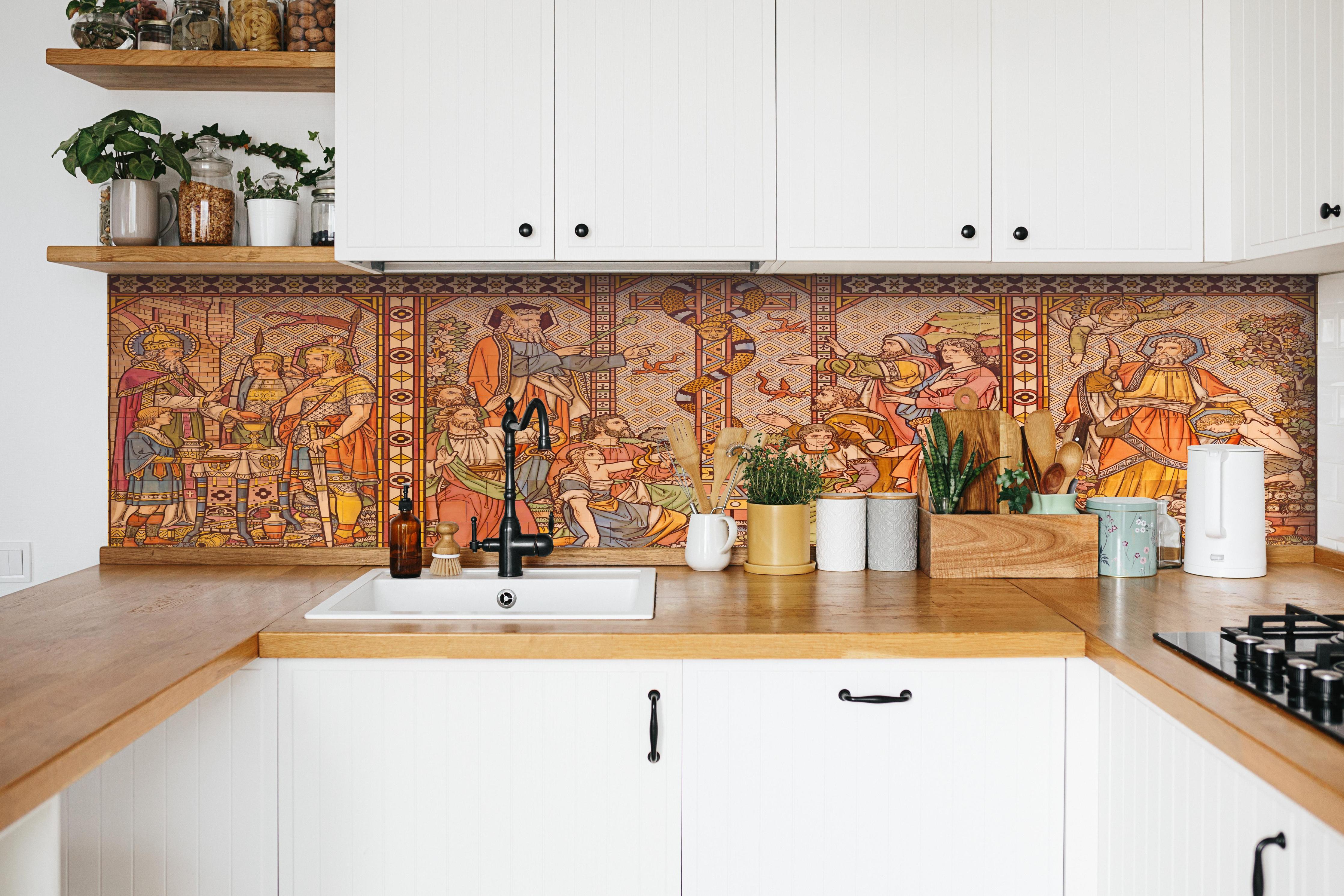 Küche - Christliches Kachelmosaik - Altes Testament hinter weißen Hochglanz-Küchenregalen und schwarzem Wasserhahn