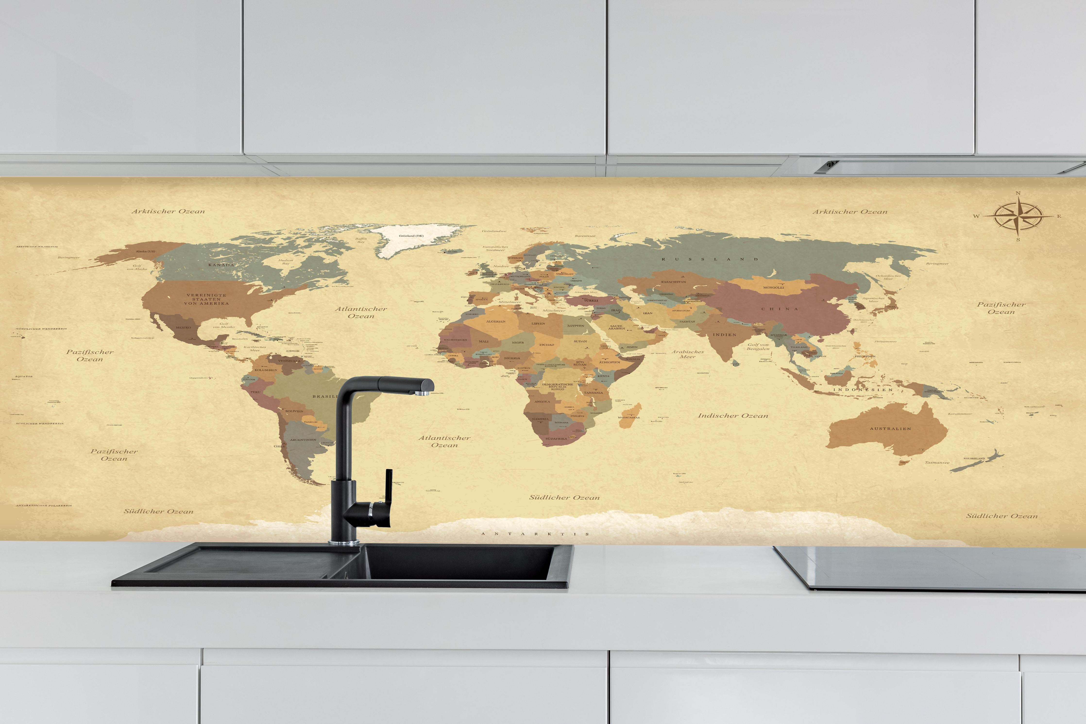 Küche - Dekorative alte Weltkarte mit Farbakzenten hinter weißen Hochglanz-Küchenregalen und schwarzem Wasserhahn