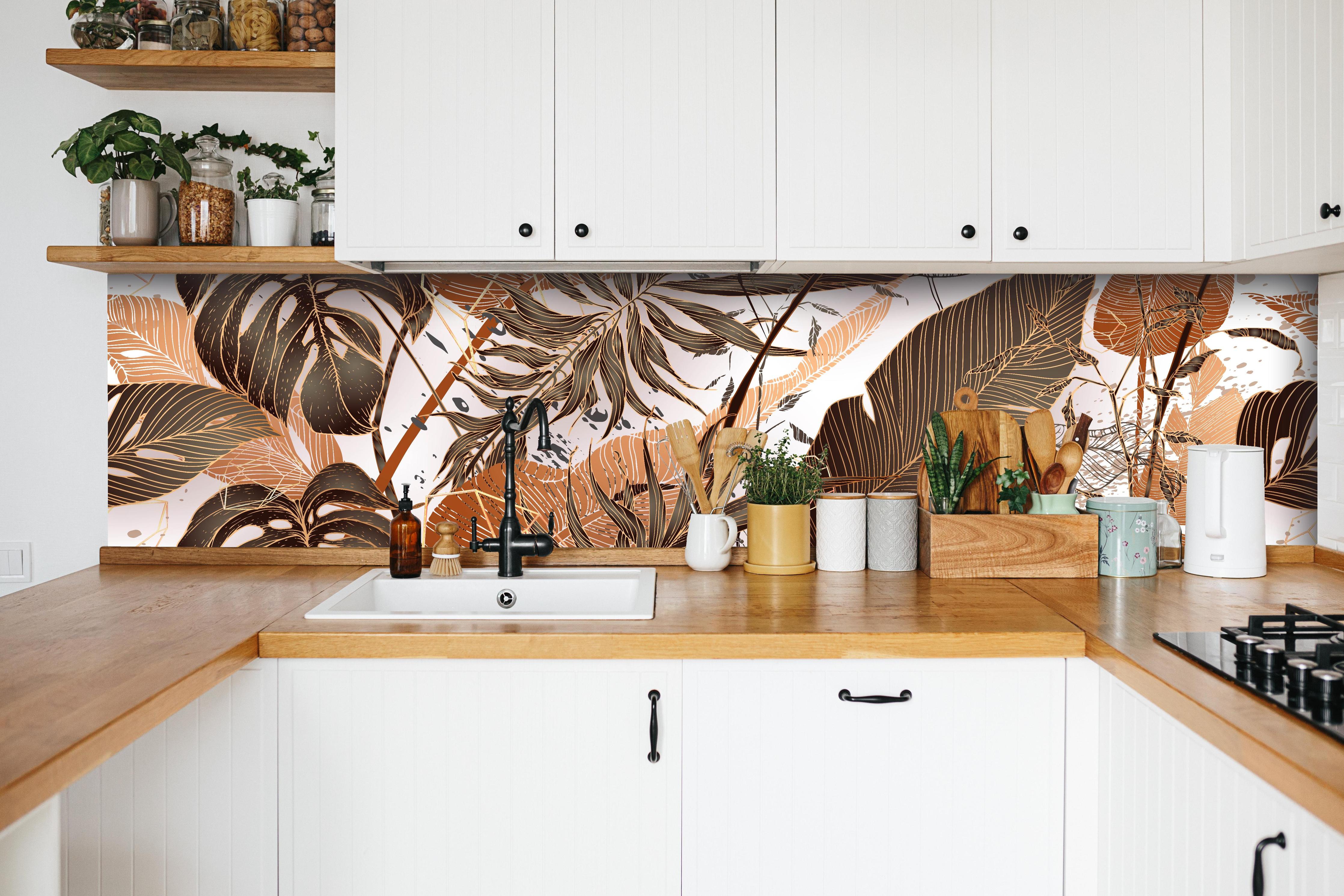 Küche - Dekoratives Blatt-Design in warmen Erdtönen hinter weißen Hochglanz-Küchenregalen und schwarzem Wasserhahn