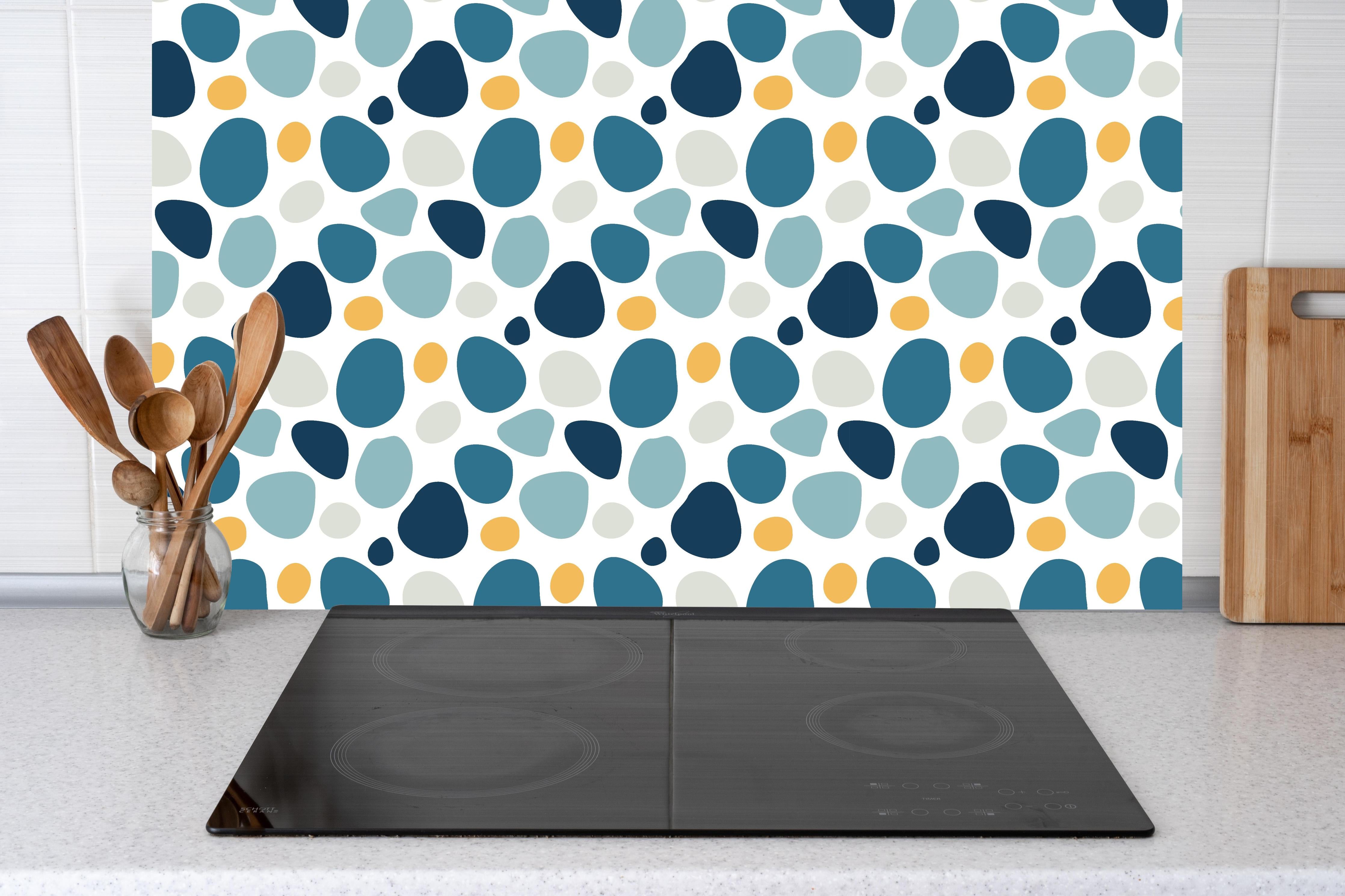 Küche - Dekoratives Blau-Weiß-Oranges Designmuster hinter weißen Hochglanz-Küchenregalen und schwarzem Wasserhahn