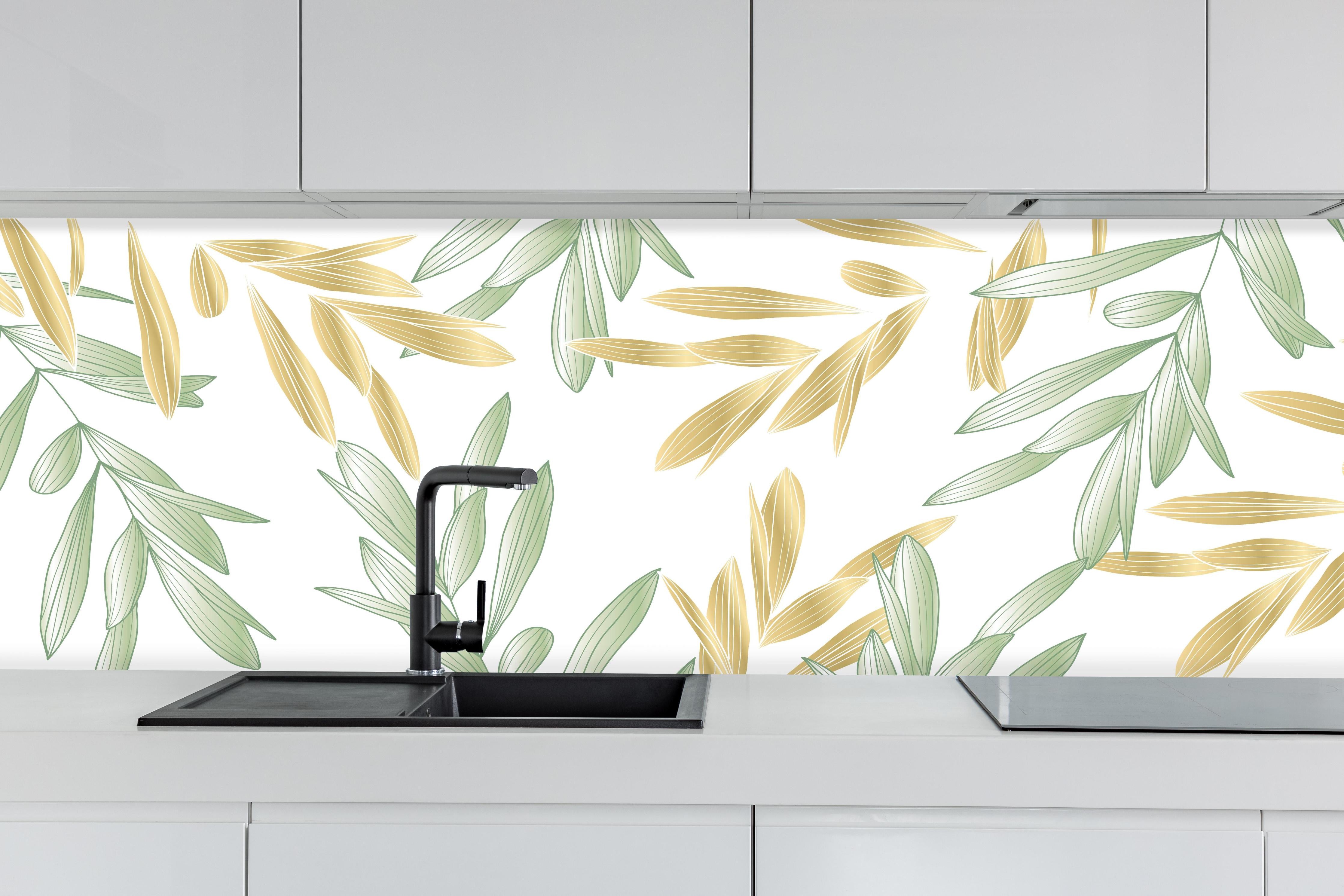 Küche - Dekoratives Grün-Gold Pflanzen-Design hinter weißen Hochglanz-Küchenregalen und schwarzem Wasserhahn