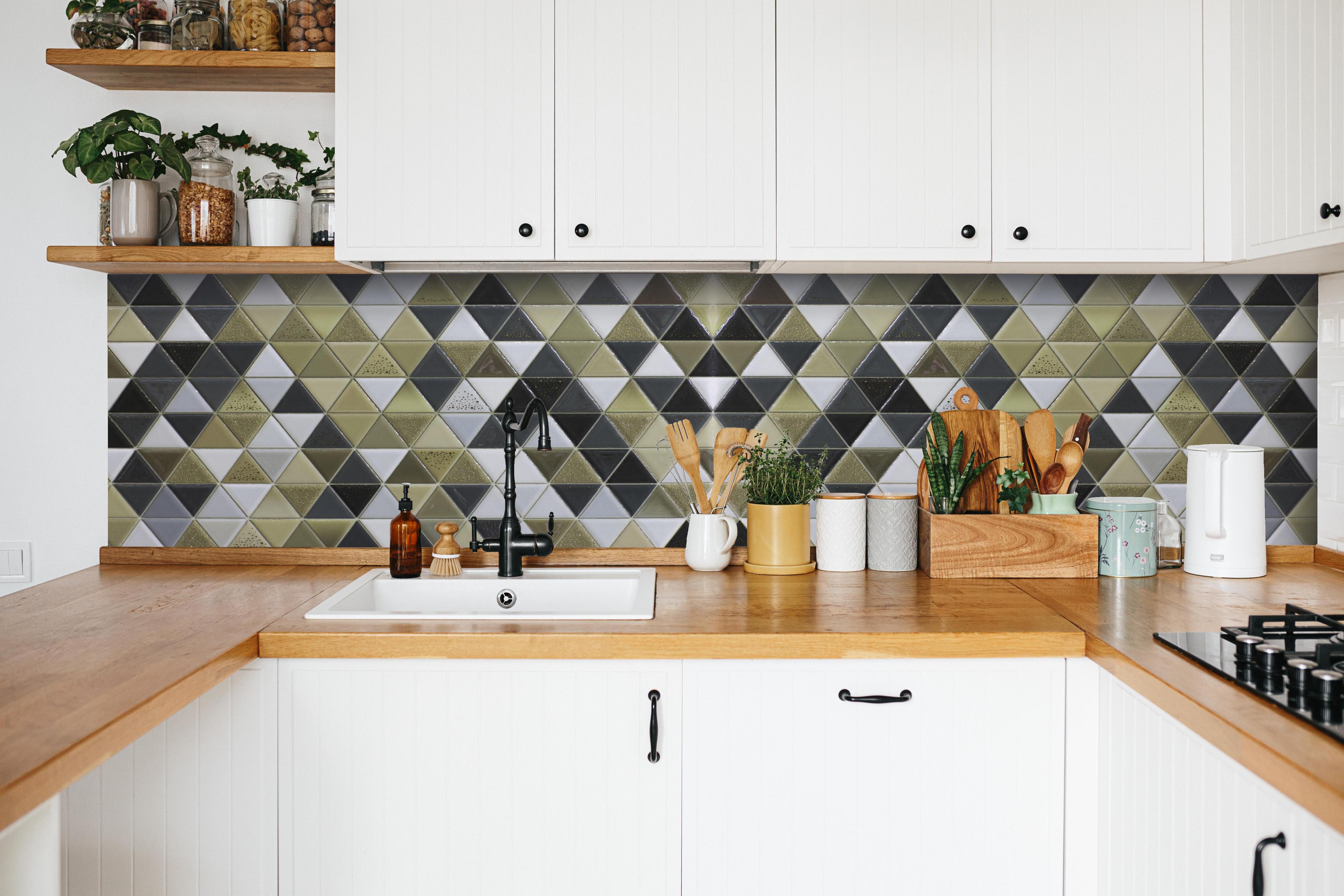 Küche - Edles Fliesen-Dekor in Schwarz, Weiß und Gold hinter weißen Hochglanz-Küchenregalen und schwarzem Wasserhahn