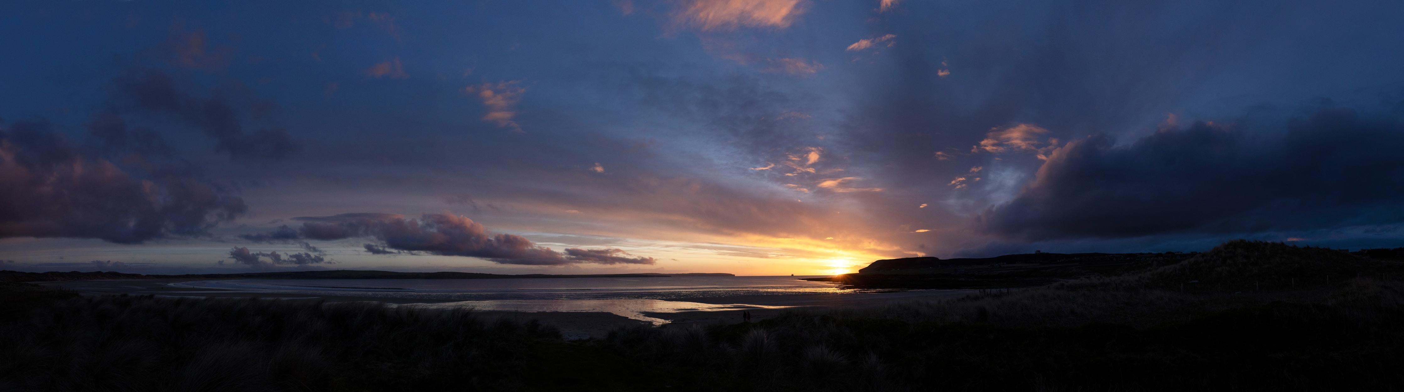Küchenrückwand-Ein malerischer Sonnenuntergang über einem ruhigen See, die Wolken leuchten in verschiedenen Blau- und Orangetönen