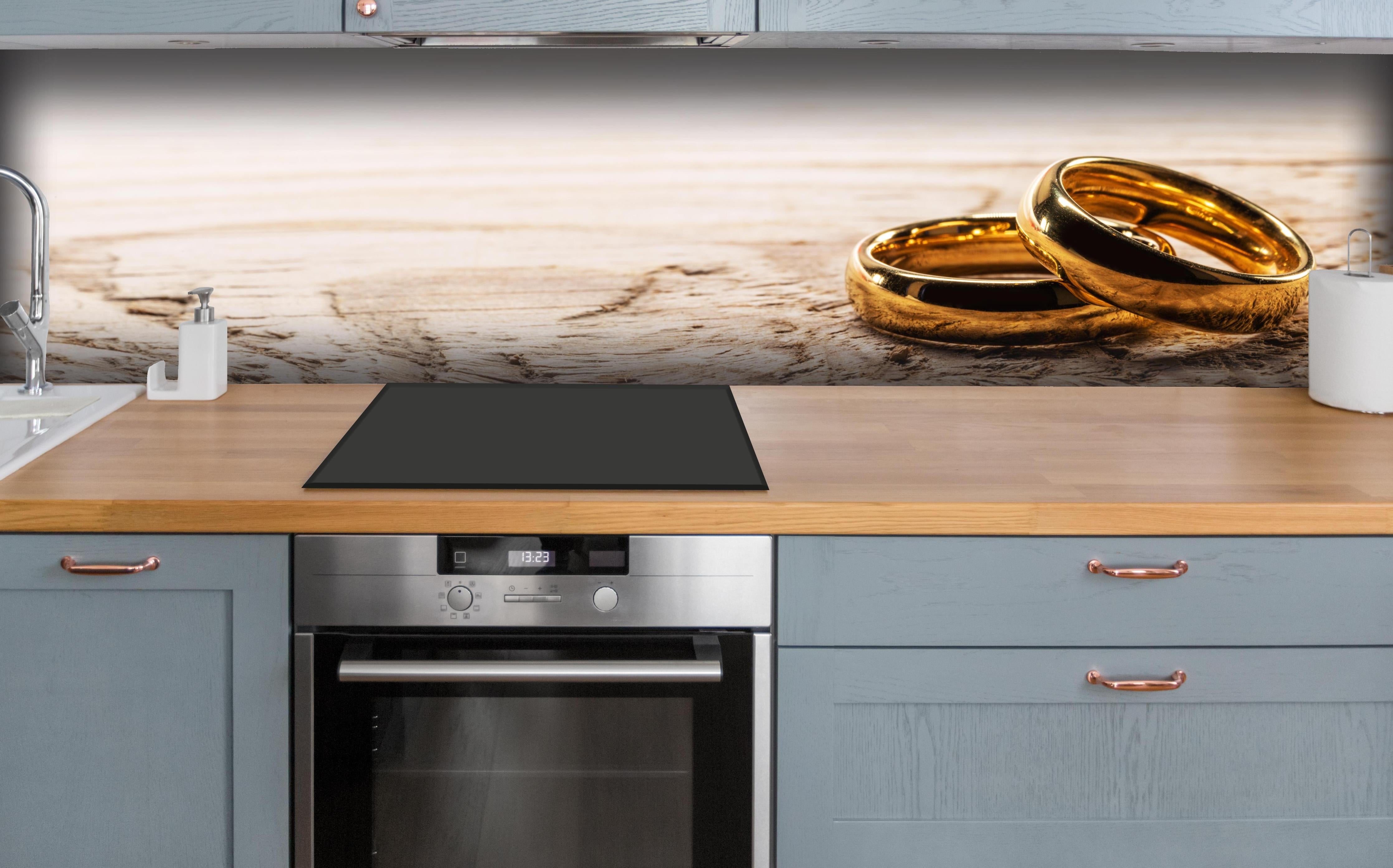 Küche - Elegante Goldringe auf rustikalem Holz hinter weißen Hochglanz-Küchenregalen und schwarzem Wasserhahn