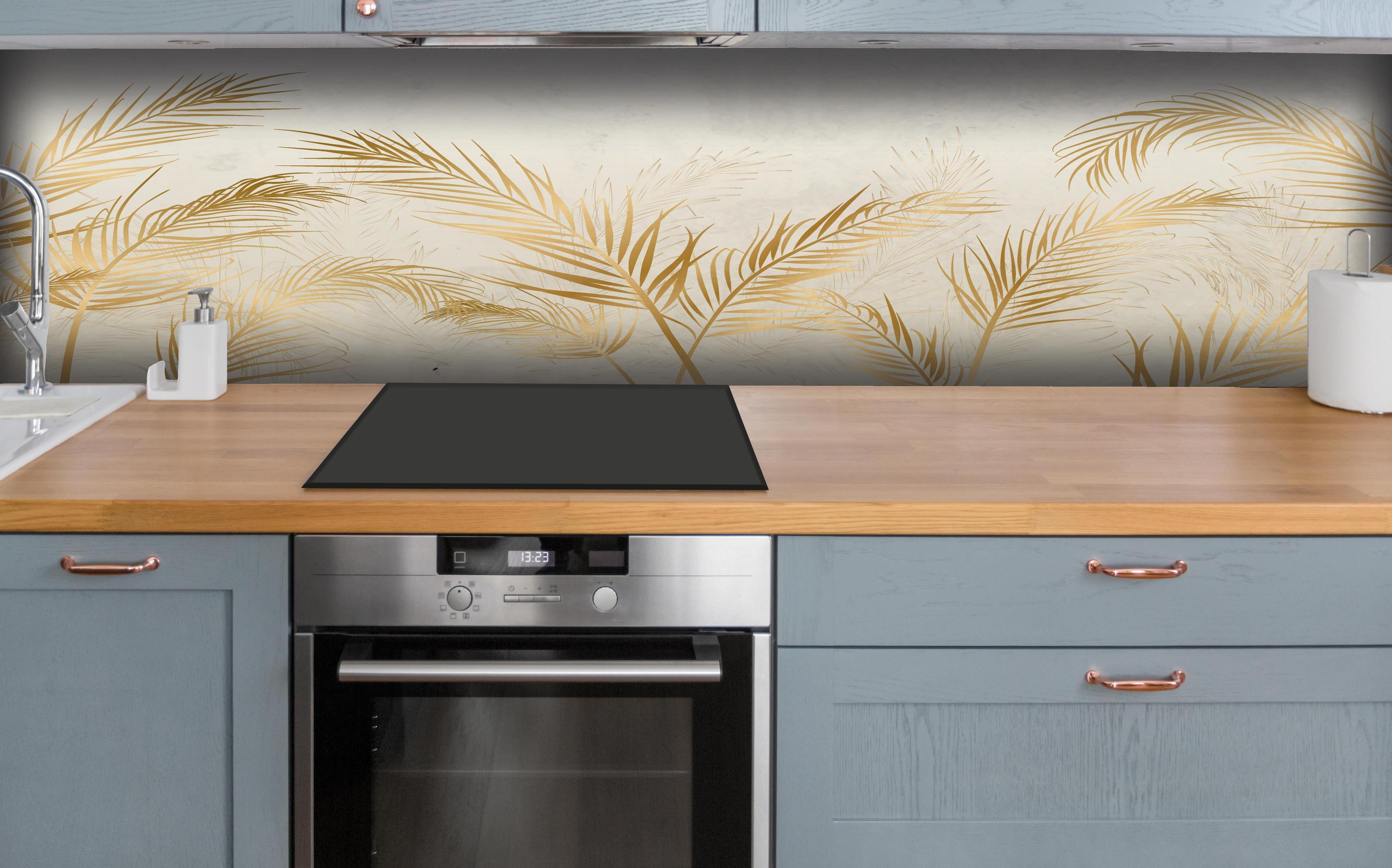 Küche - Elegante goldene Palmwedel auf hellem Grund hinter weißen Hochglanz-Küchenregalen und schwarzem Wasserhahn