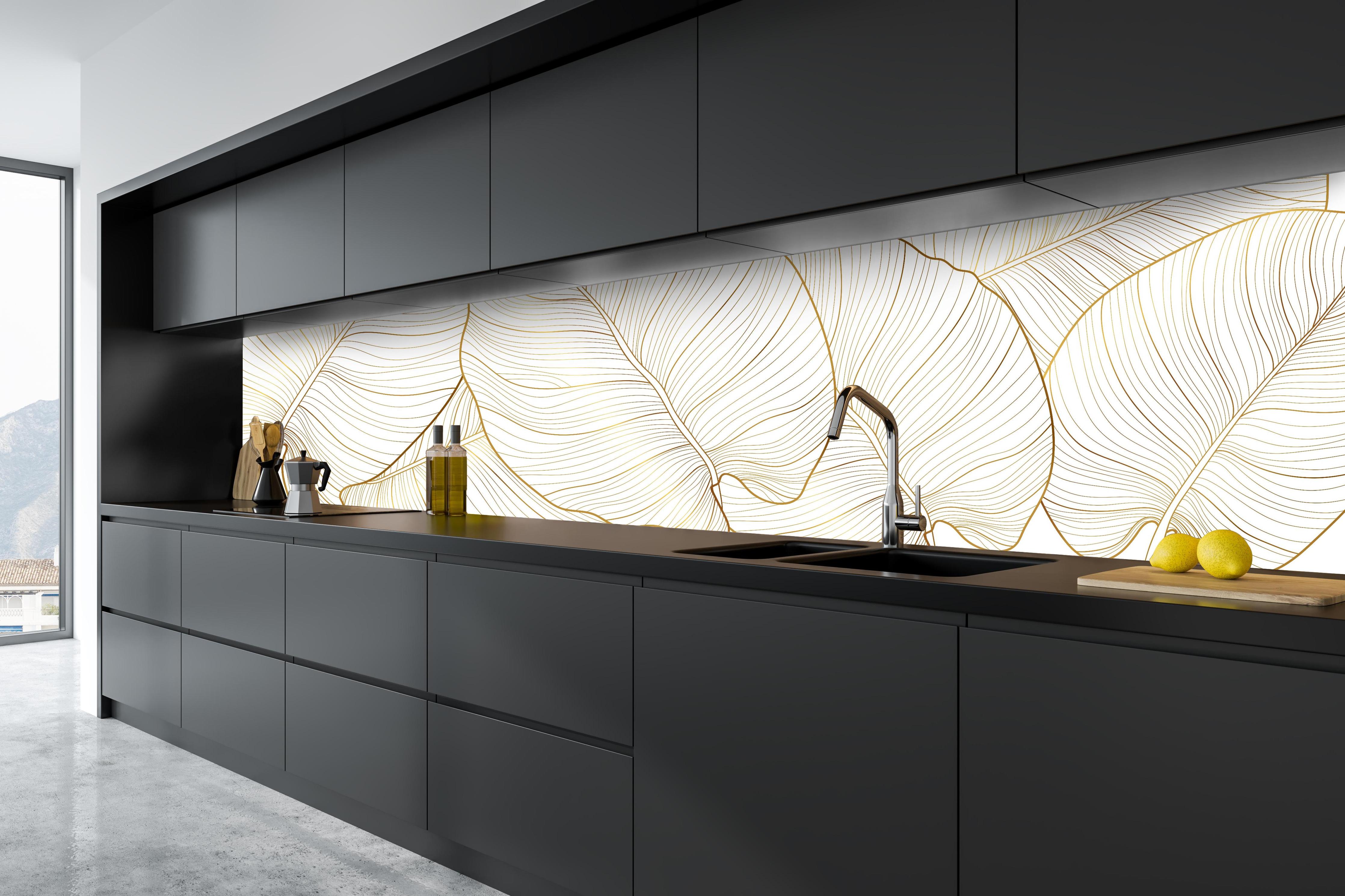 Küche - Elegantes Blatt-Design in Gold und Weiß hinter weißen Hochglanz-Küchenregalen und schwarzem Wasserhahn