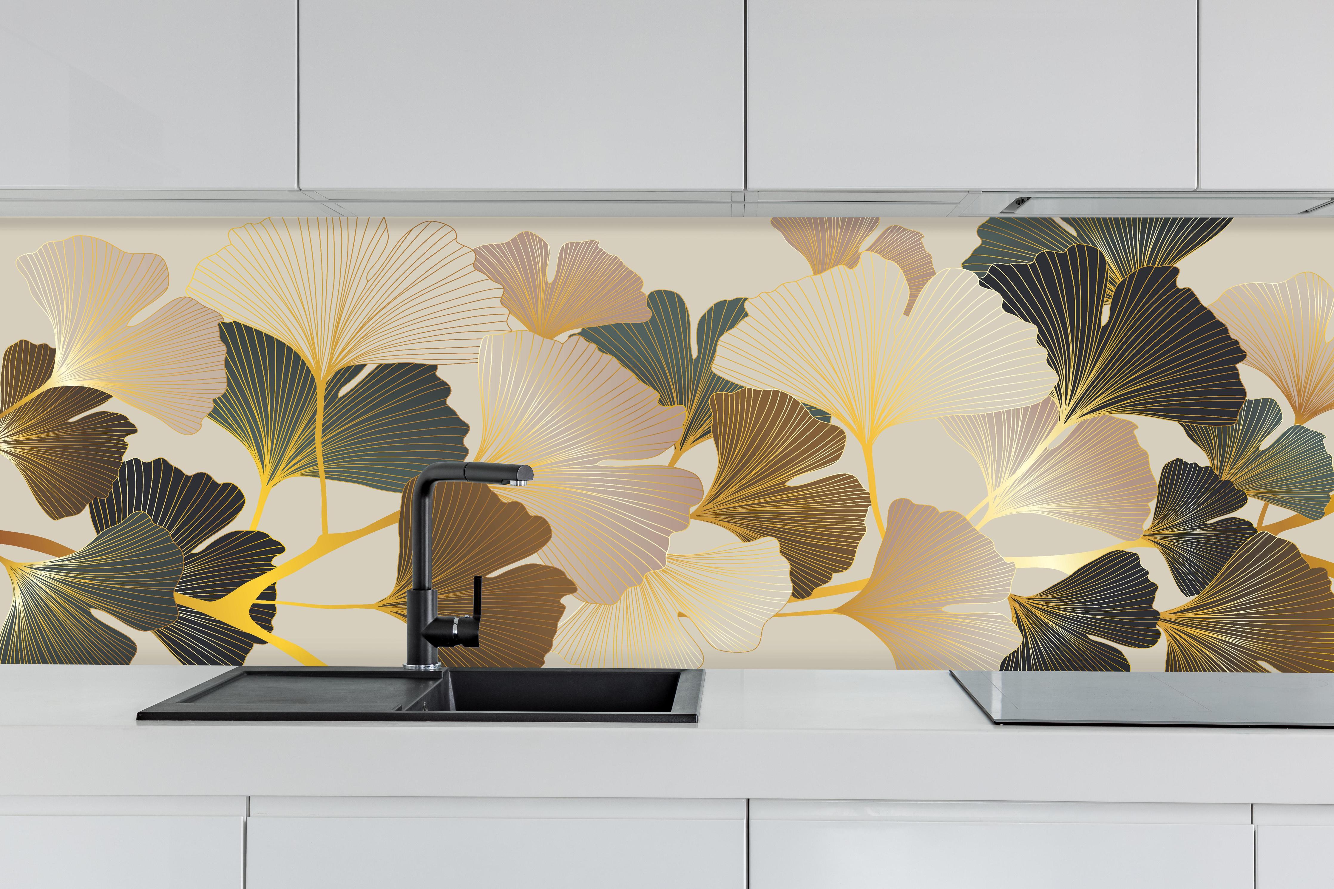 Küche - Elegantes Ginkgo-Blattmotiv mit goldfarbenen Akzenten hinter weißen Hochglanz-Küchenregalen und schwarzem Wasserhahn