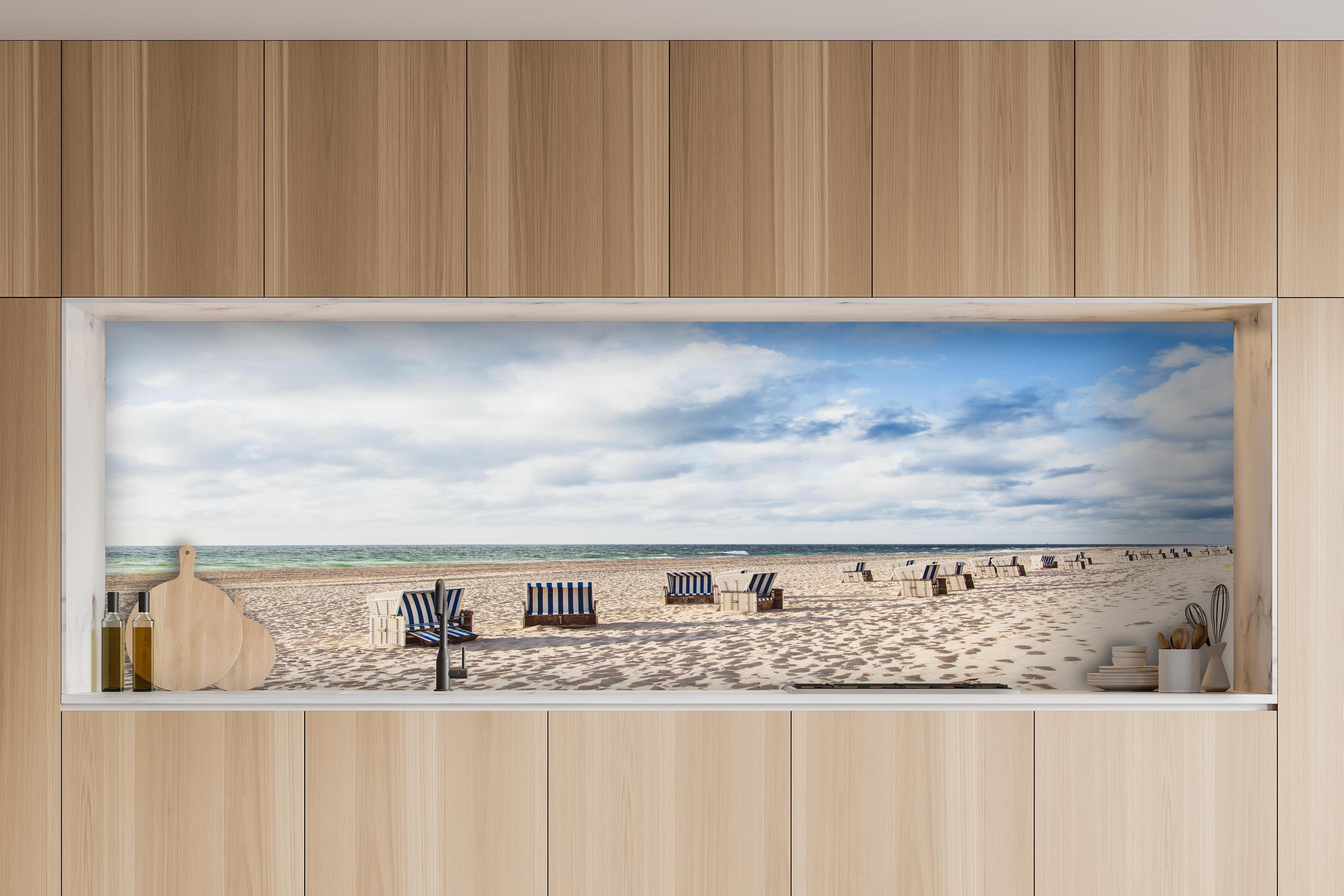 Küche - Entspannte Strandatmosphäre mit blauen und weißen Liegestühlen am Meer hinter weißen Hochglanz-Küchenregalen und schwarzem Wasserhahn