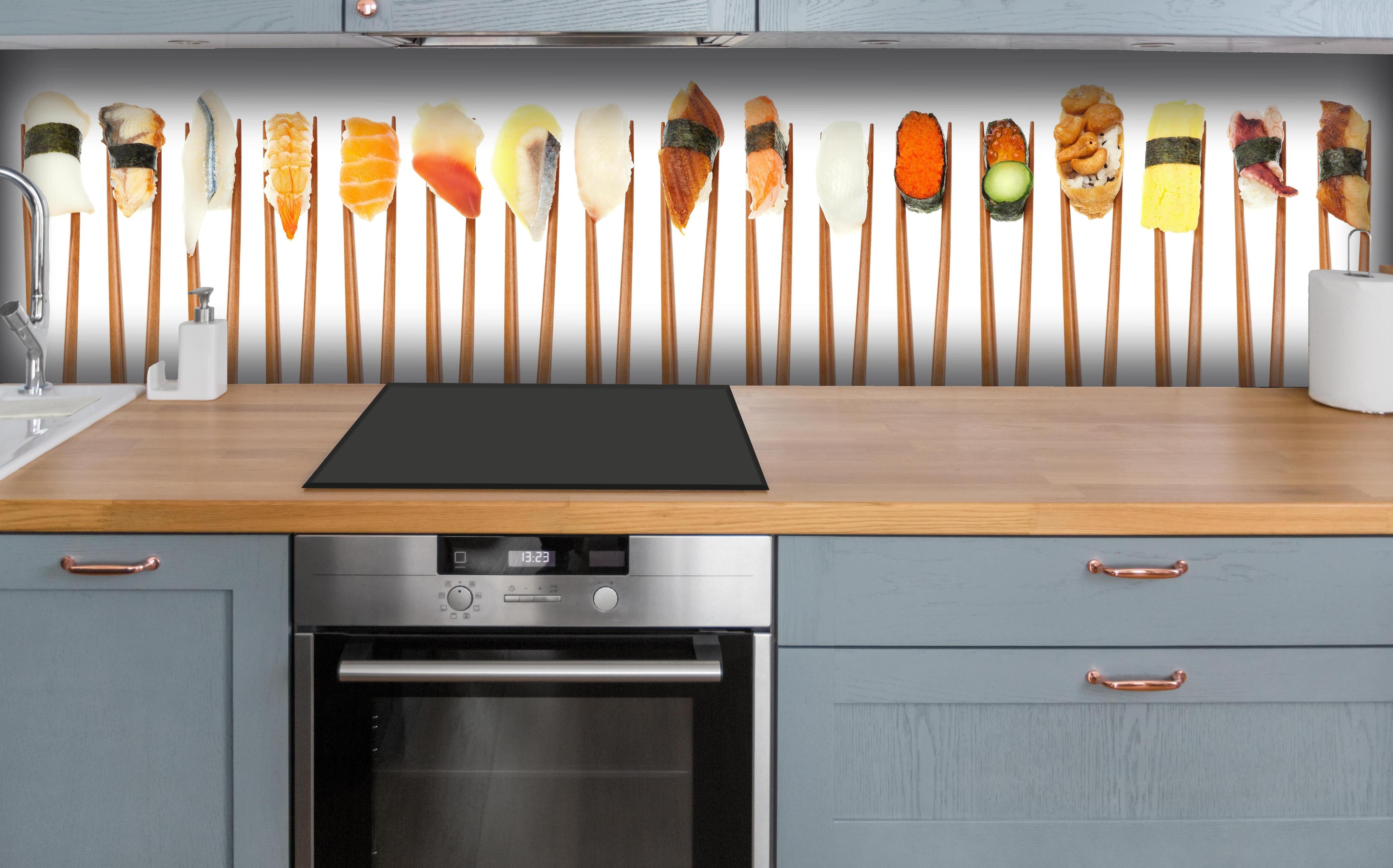 Küche - Exquisite Auswahl an buntem Sushi auf Stäbchen hinter weißen Hochglanz-Küchenregalen und schwarzem Wasserhahn