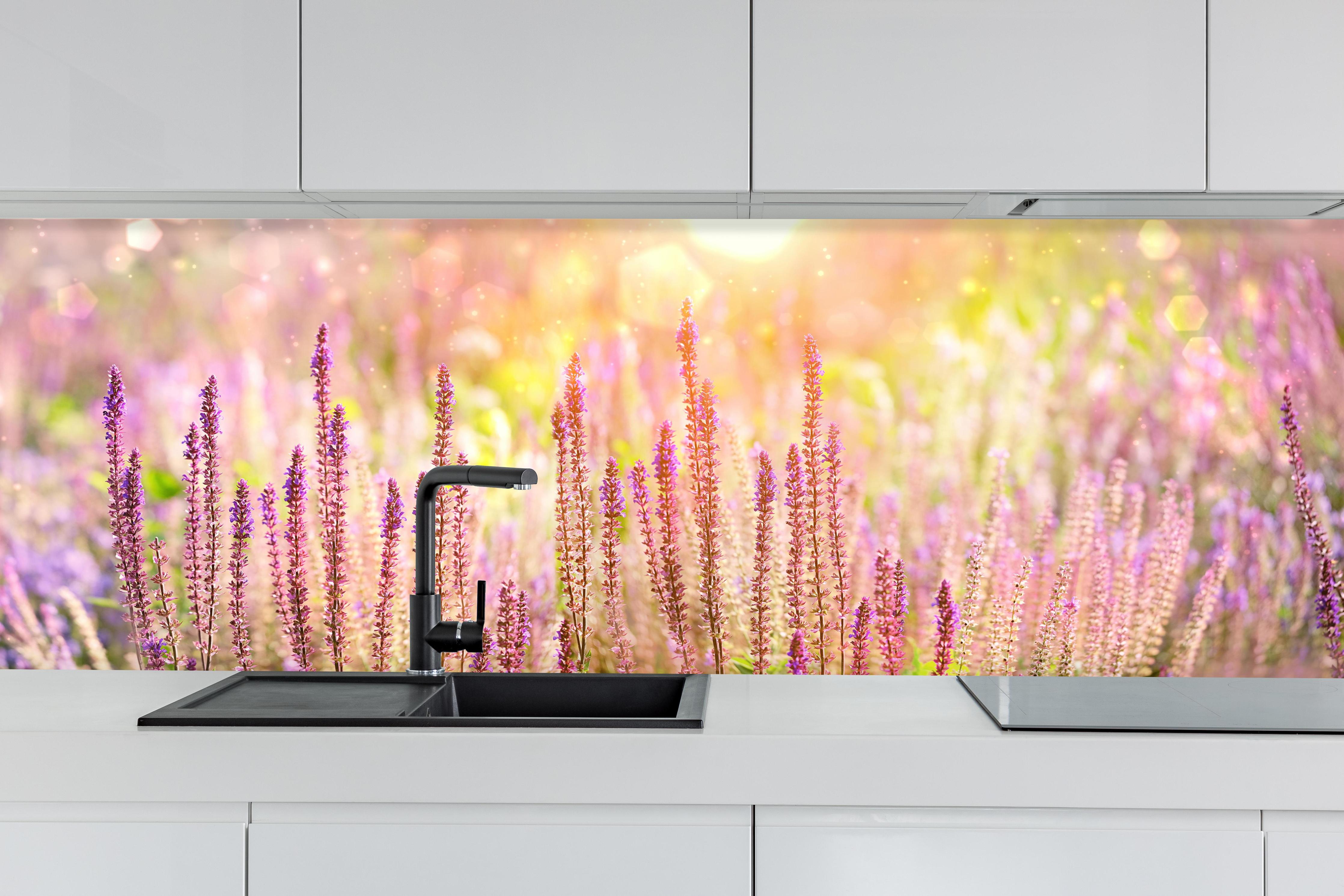 Küche - Farbenfrohe Blüten der Ziersalbei-Pflanzen hinter weißen Hochglanz-Küchenregalen und schwarzem Wasserhahn