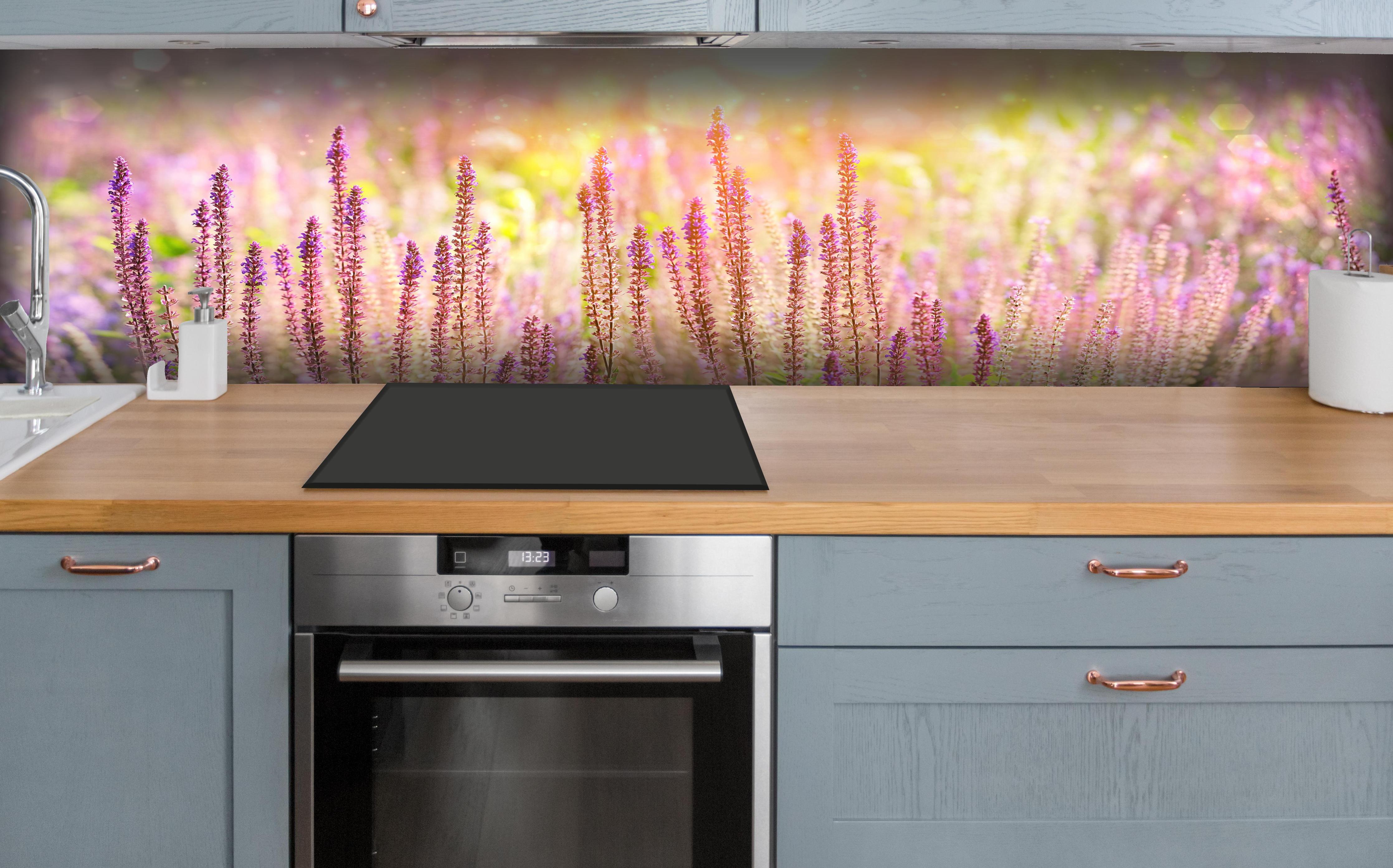 Küche - Farbenfrohe Blüten der Ziersalbei-Pflanzen hinter weißen Hochglanz-Küchenregalen und schwarzem Wasserhahn