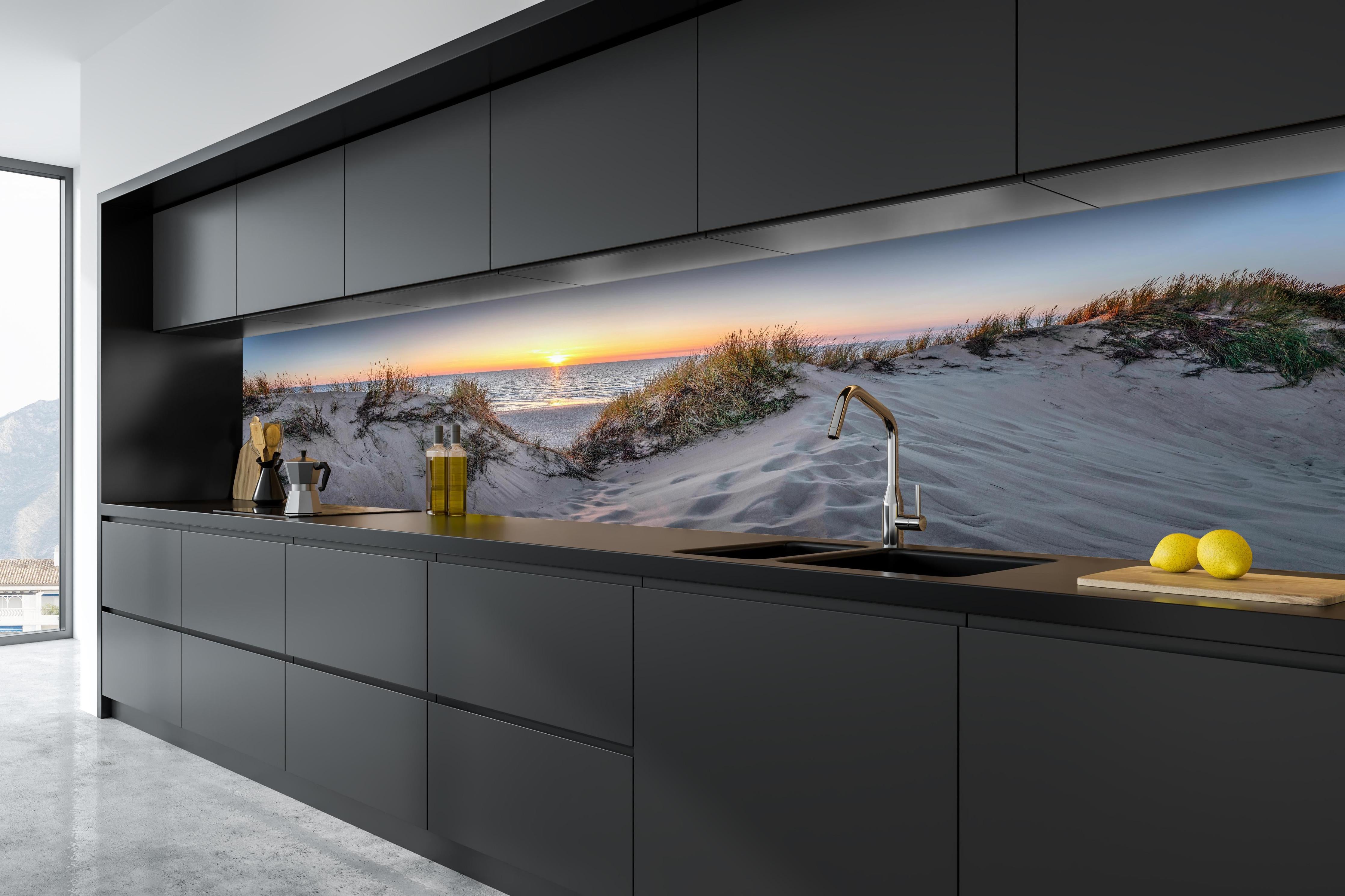 Küche - Faszinierender Sonnenuntergang über einer Sanddüne am Meer hinter weißen Hochglanz-Küchenregalen und schwarzem Wasserhahn