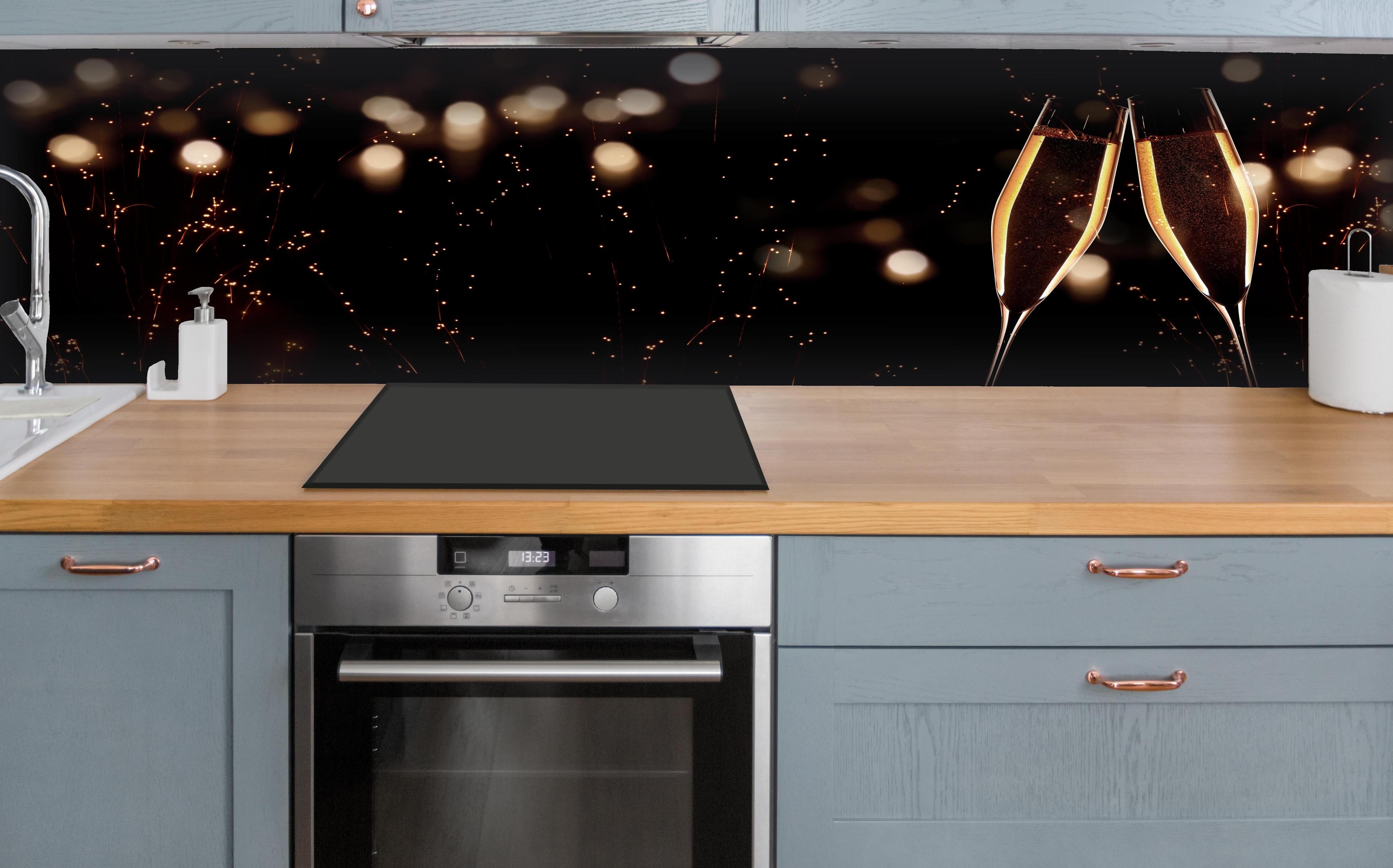 Küche - Feierlicher Champagner-Clink bei Jahreswechsel hinter weißen Hochglanz-Küchenregalen und schwarzem Wasserhahn