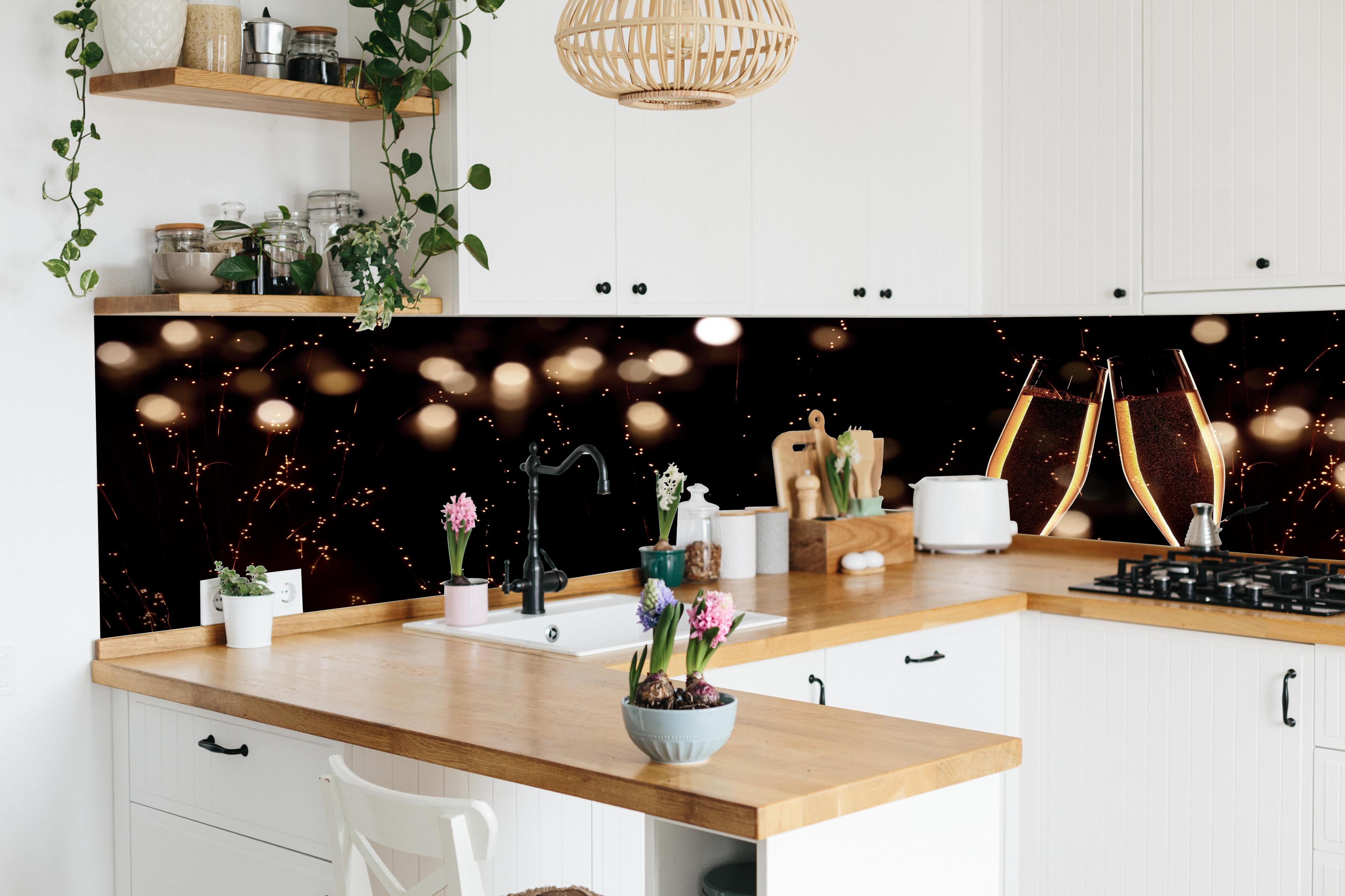 Küche - Feierlicher Champagner-Clink bei Jahreswechsel hinter weißen Hochglanz-Küchenregalen und schwarzem Wasserhahn