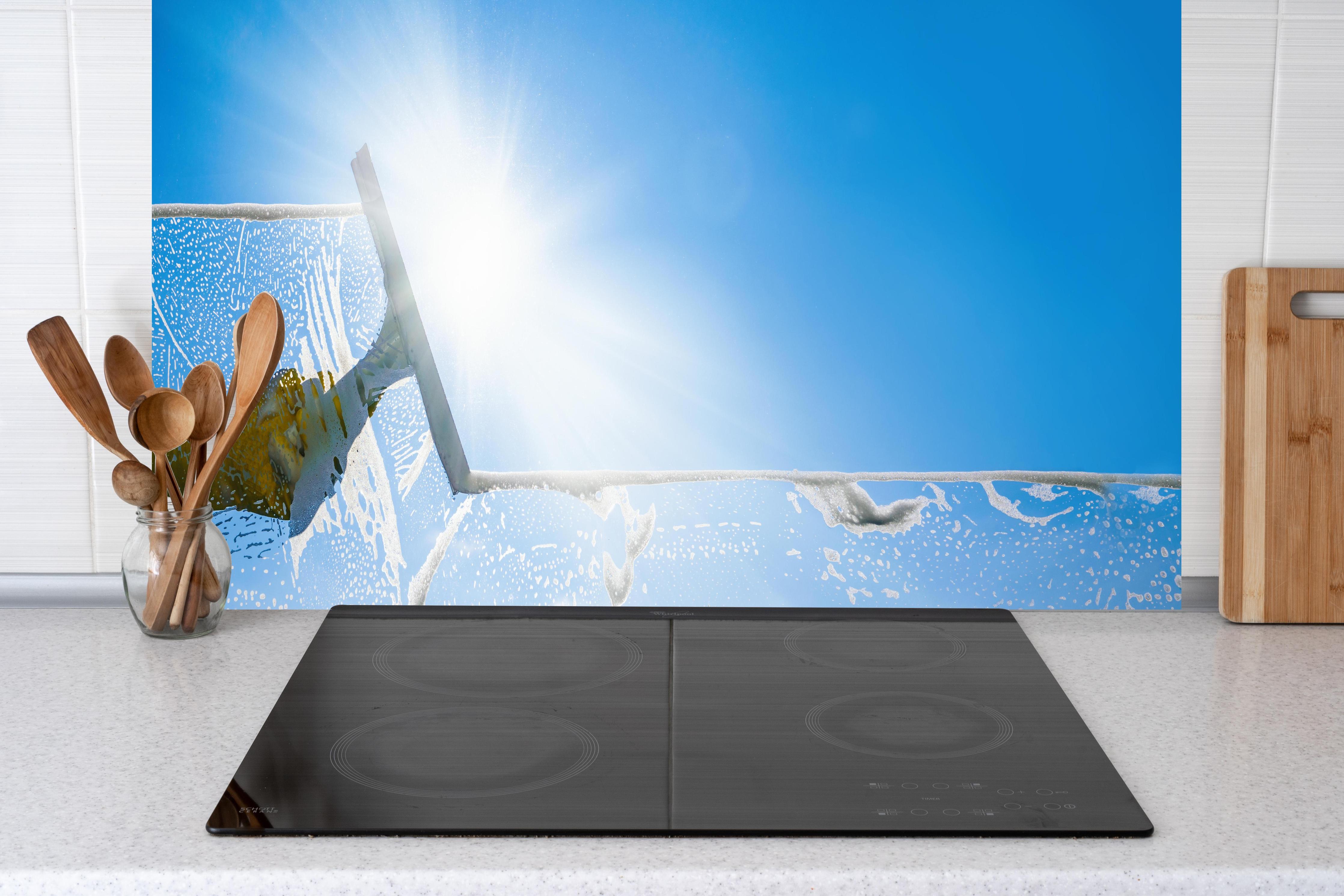 Küche - Fensterputzer mit Abzieher und strahlendem Himmel hinter weißen Hochglanz-Küchenregalen und schwarzem Wasserhahn