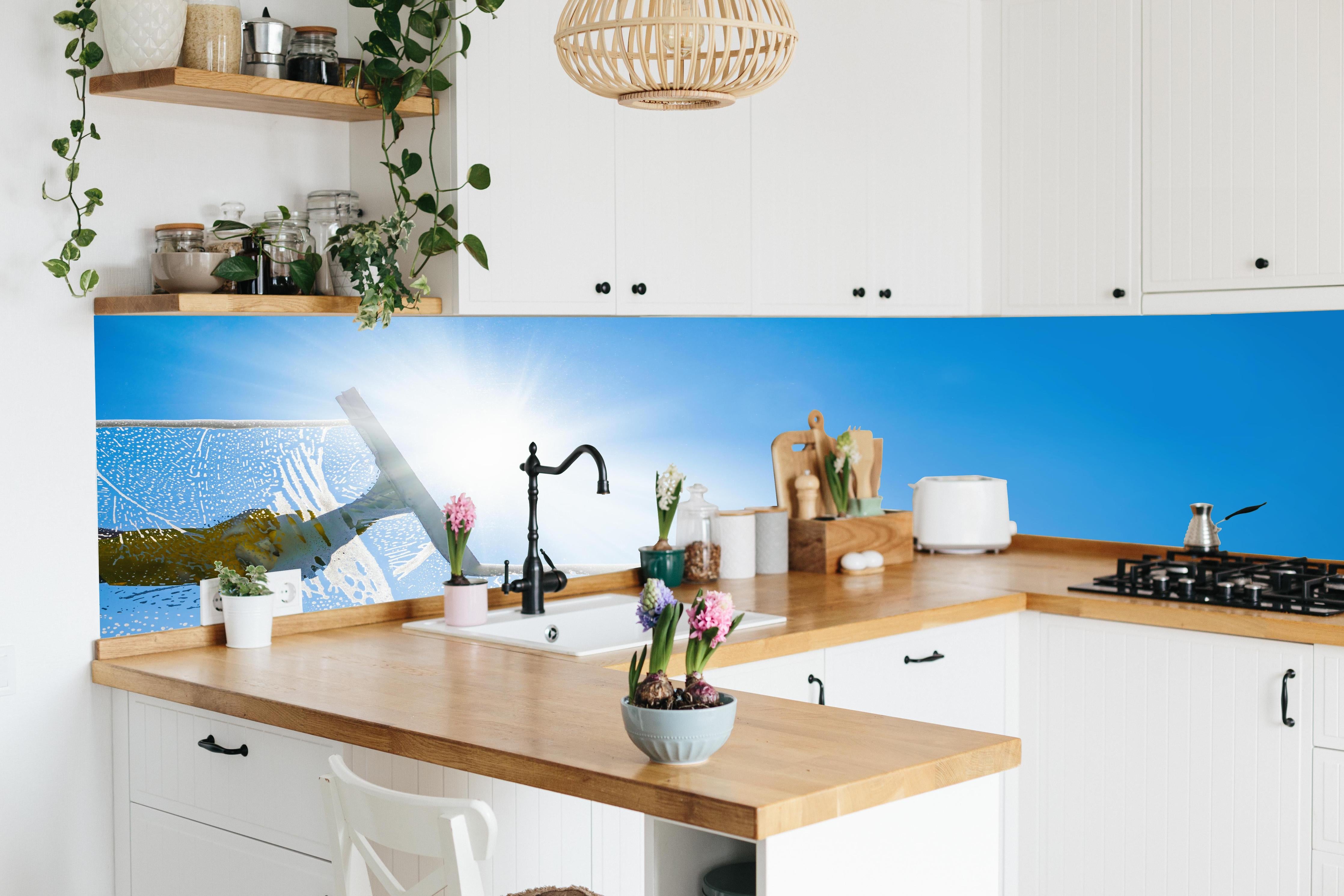 Küche - Fensterputzer mit Abzieher und strahlendem Himmel hinter weißen Hochglanz-Küchenregalen und schwarzem Wasserhahn