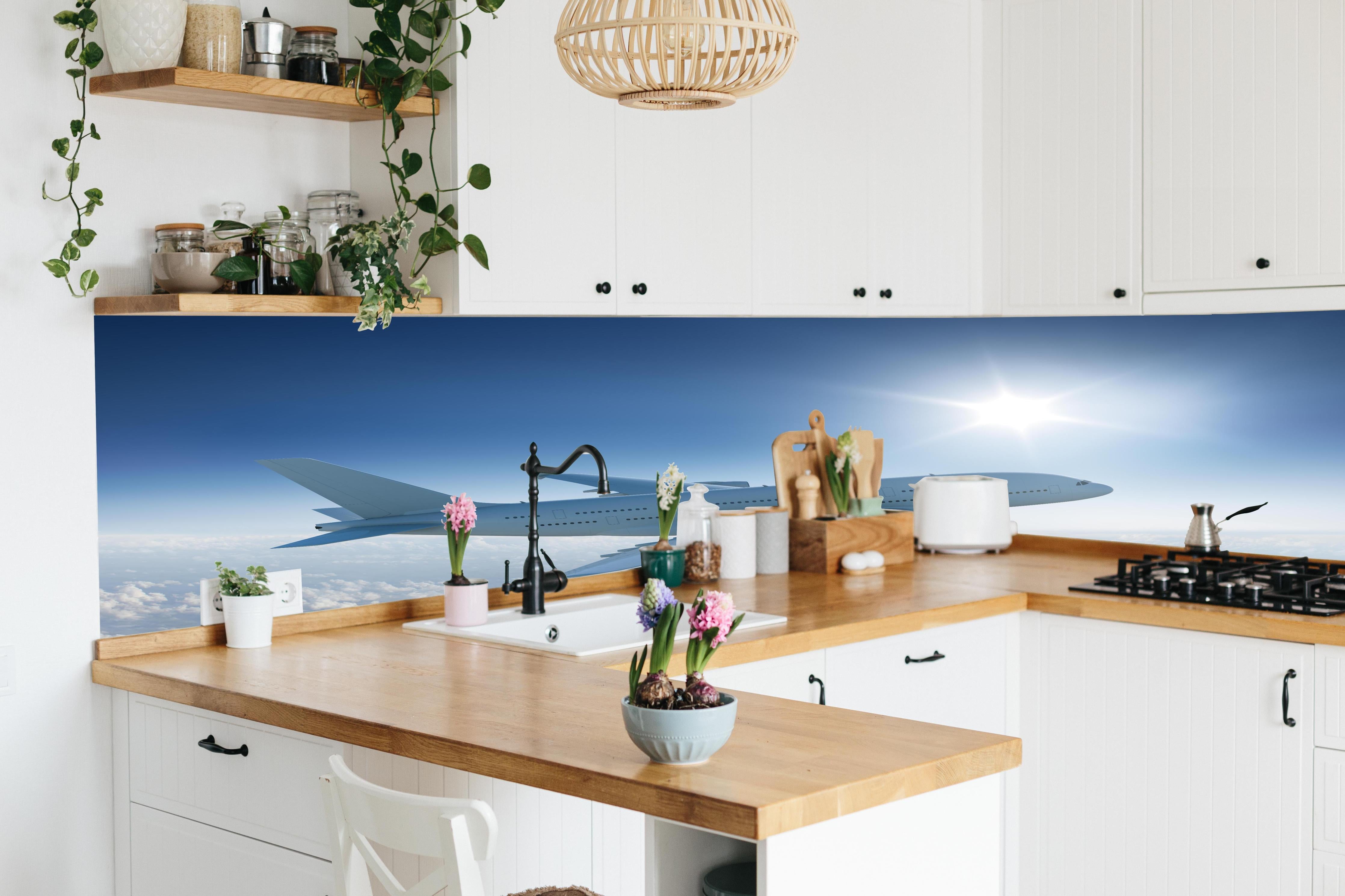 Küche - Flugzeug über weißen Wolken hinter weißen Hochglanz-Küchenregalen und schwarzem Wasserhahn