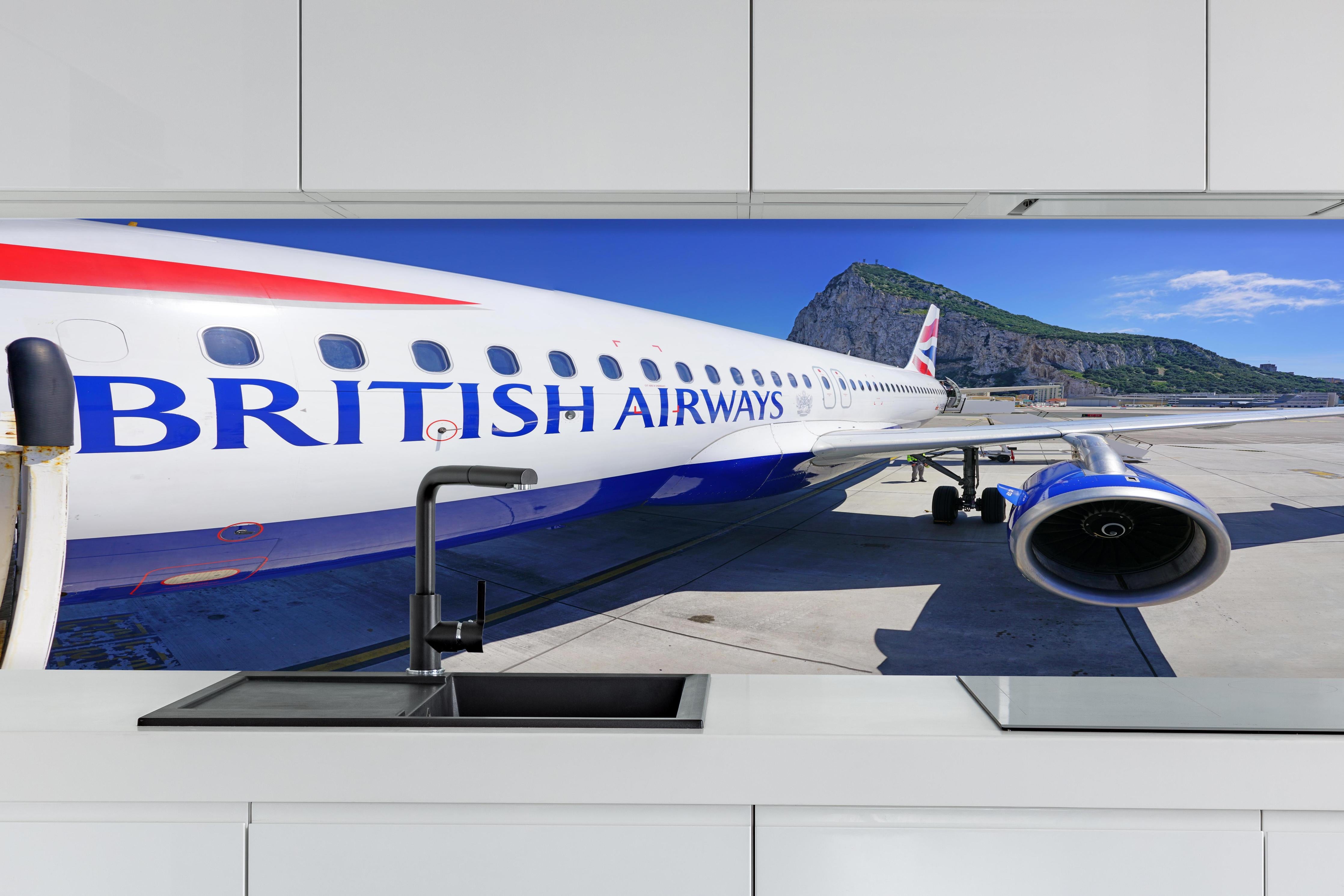 Küche - Flugzeug von British Airways hinter weißen Hochglanz-Küchenregalen und schwarzem Wasserhahn