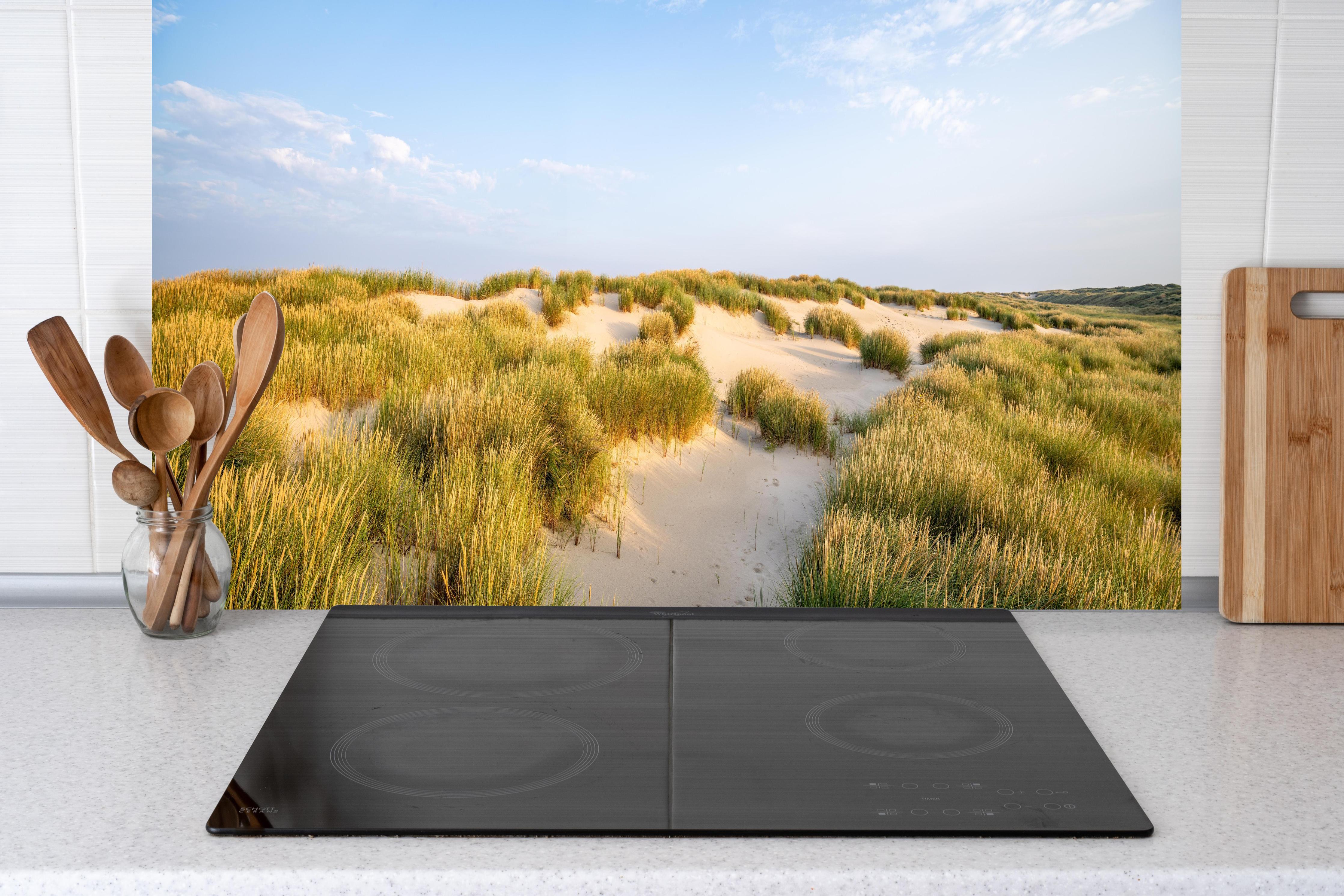 Küche - Friedliche Dünenlandschaft mit leuchtendem Gras im warmen Sonnenlicht hinter weißen Hochglanz-Küchenregalen und schwarzem Wasserhahn