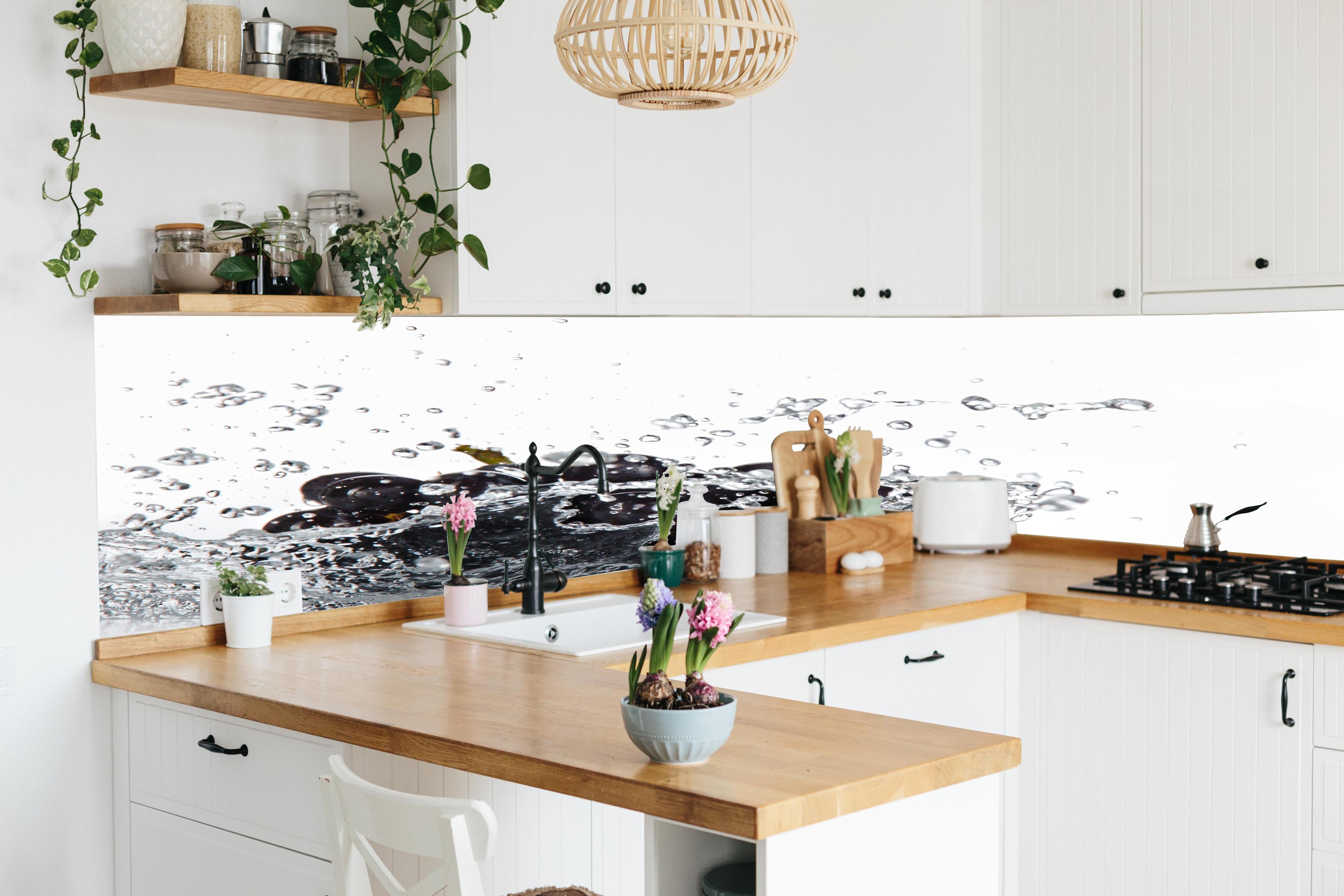 Küche - Frische Trauben im Wasser Splash hinter weißen Hochglanz-Küchenregalen und schwarzem Wasserhahn