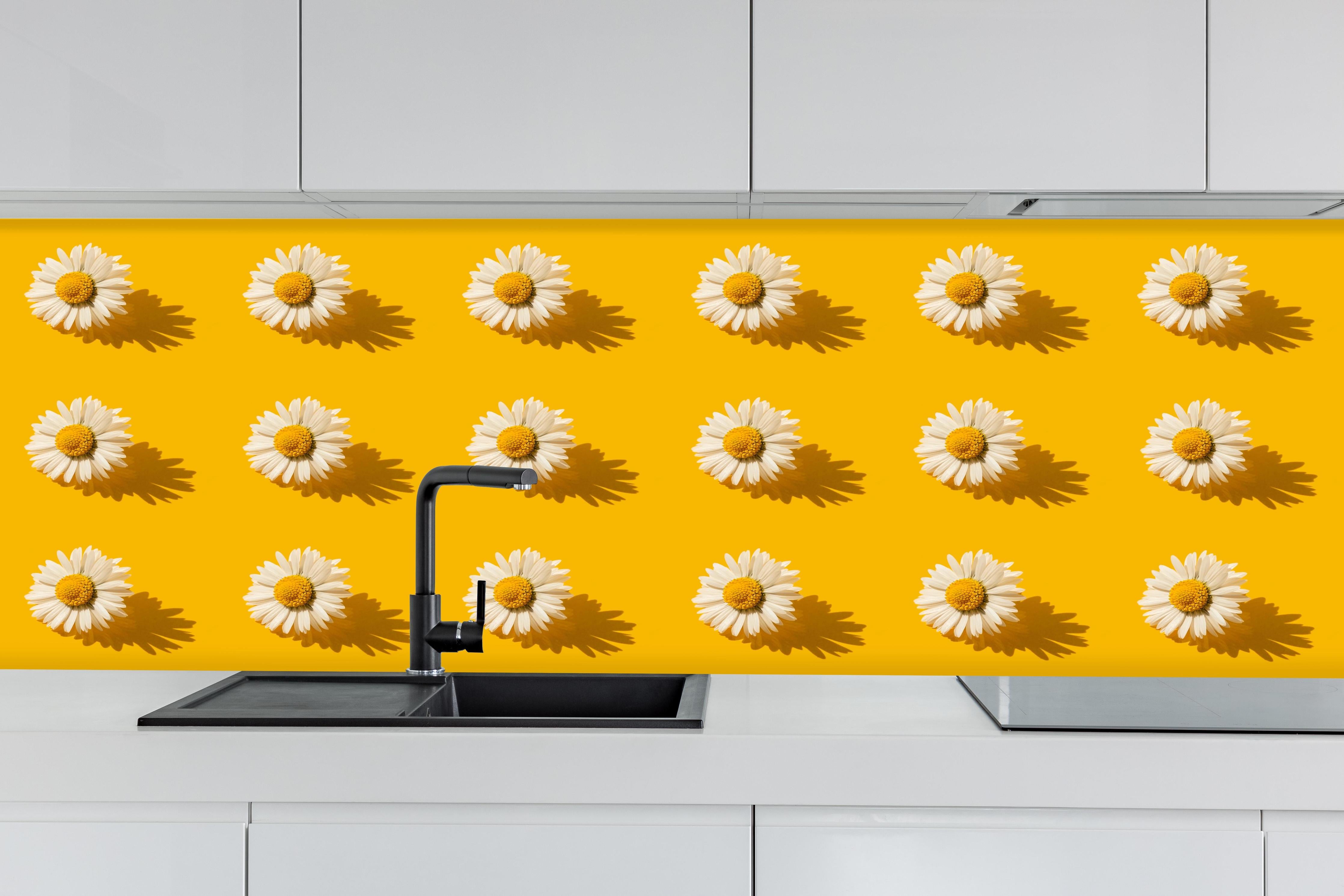 Küche - Gänseblümchen Muster auf gelbem Hintergrund hinter weißen Hochglanz-Küchenregalen und schwarzem Wasserhahn