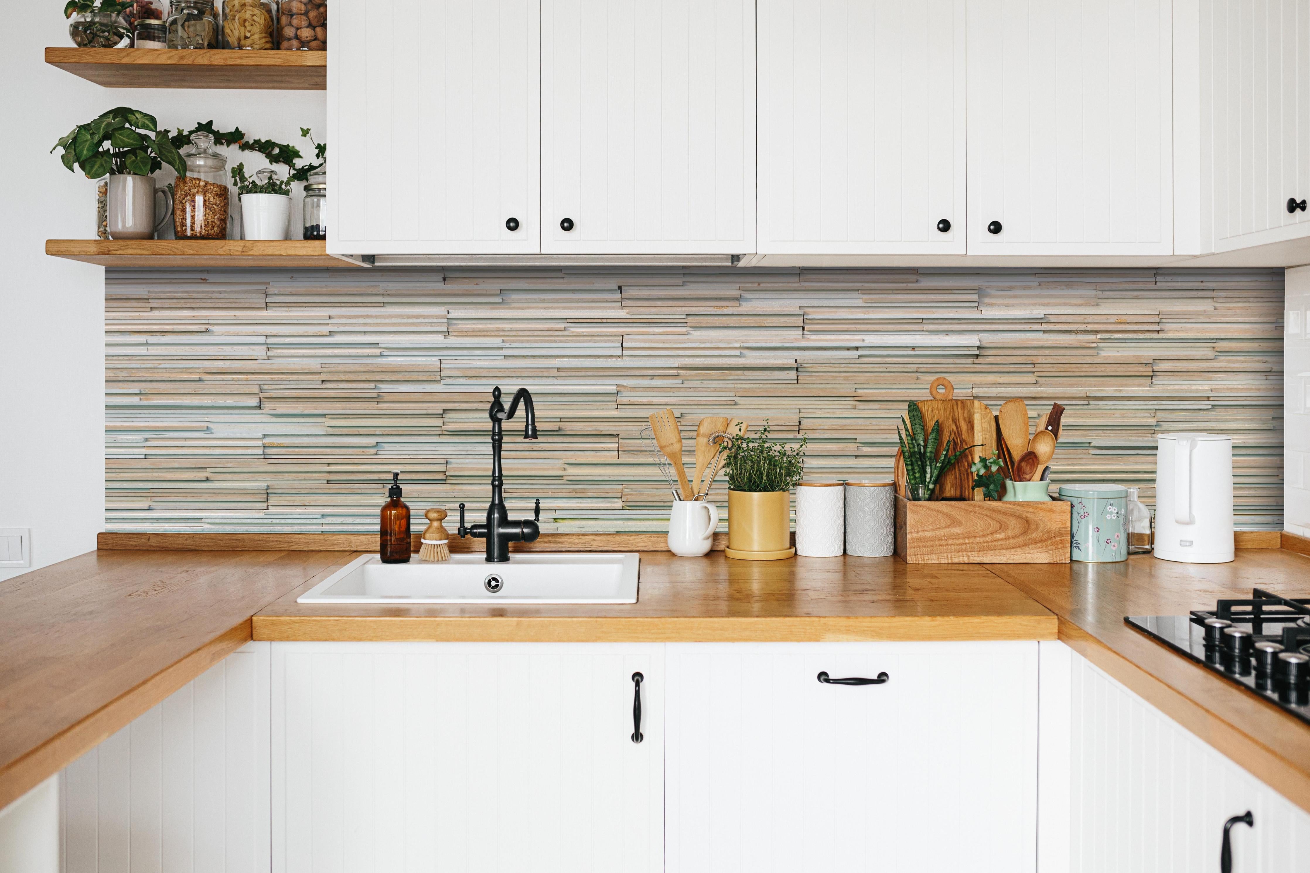 Küche - Gestapelte Holzplatten Wandverkleidung Natur Look hinter weißen Hochglanz-Küchenregalen und schwarzem Wasserhahn